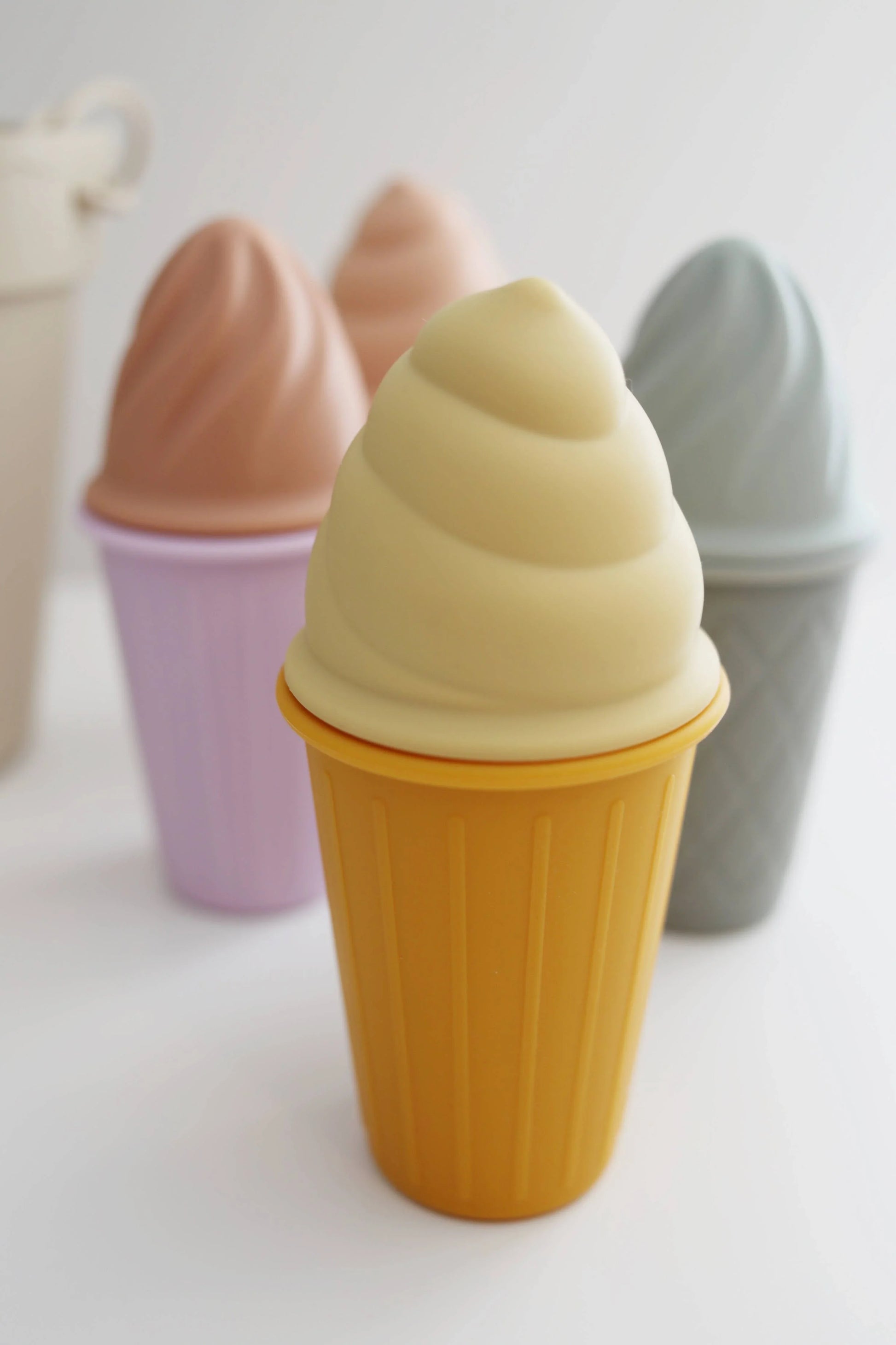Soft pastel silicone ice cream cup toys in yellow, purple, and gray colors. Come see us at Awaken, Franklin, Tennessee