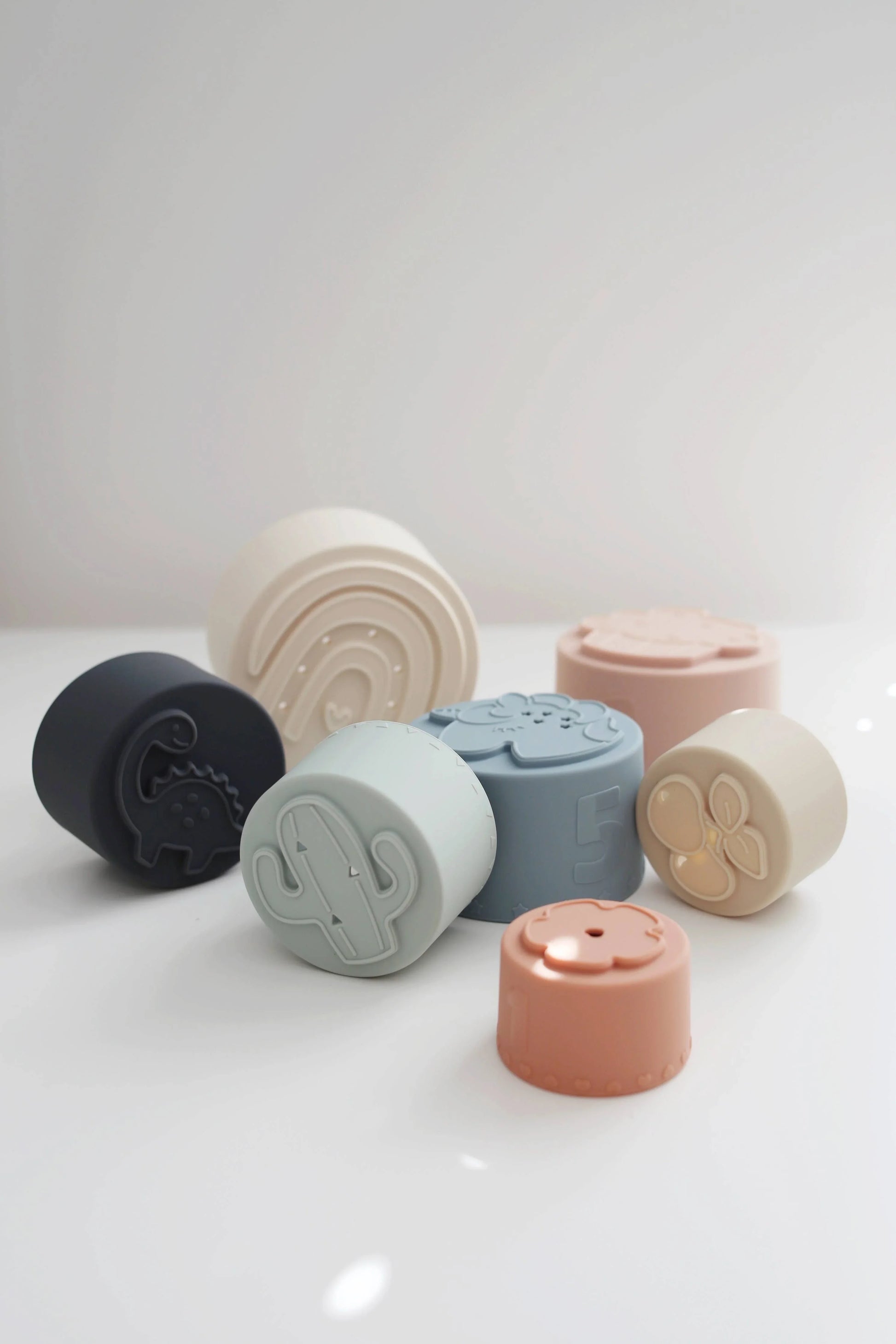 Pastel-colored silicone stacking cups with shapes and numbers on white surface. Come see us at Awaken, Franklin, Tennessee
