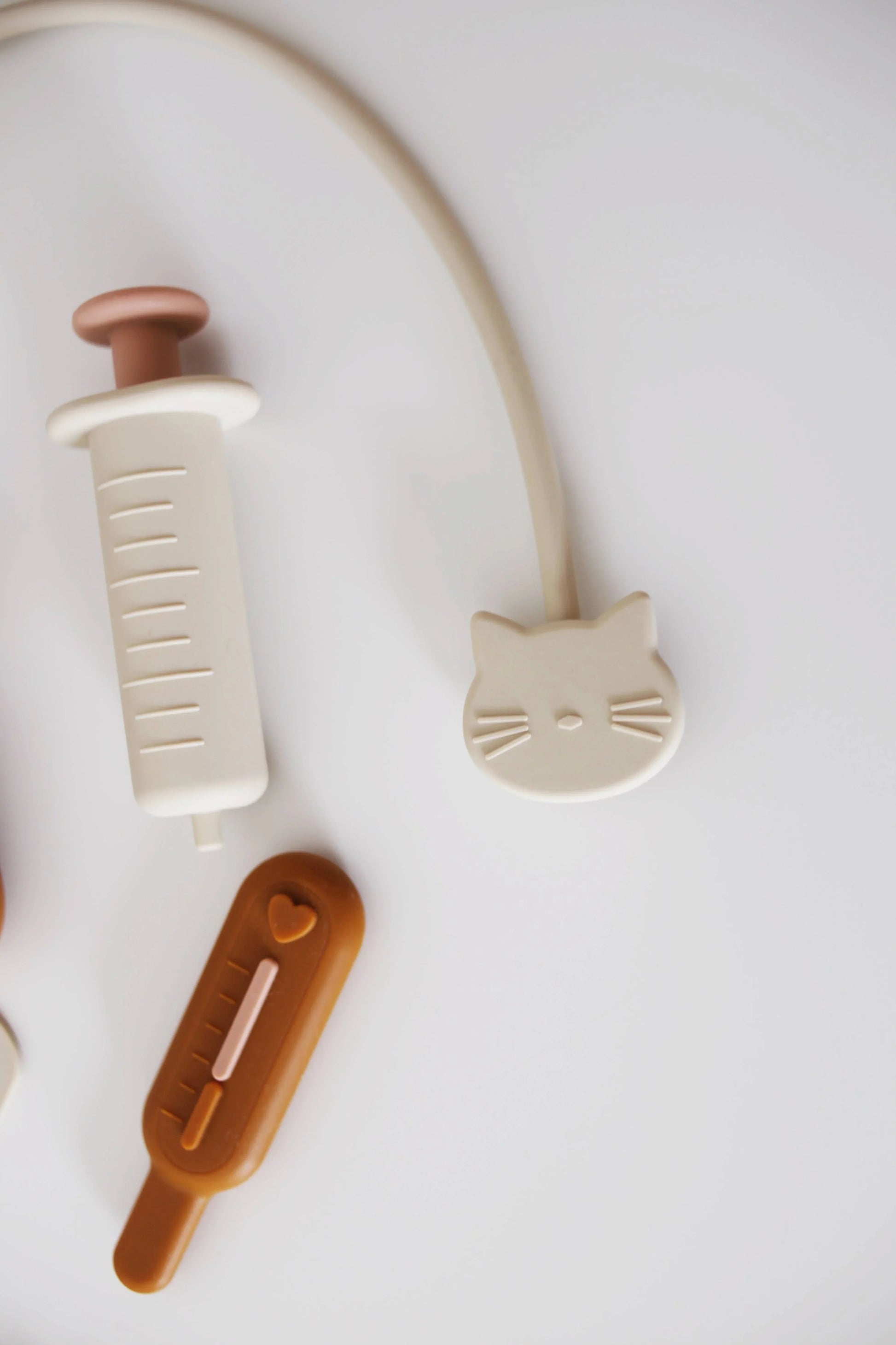 Cute silicone cat-shaped stethoscope, syringe and thermometer toy on white background. Come see us at Awaken, Franklin, Tennessee