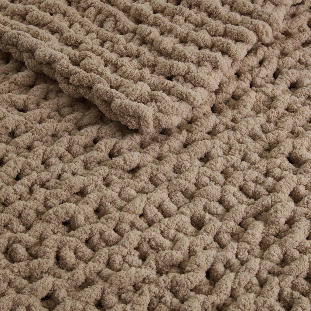 Close-up of a chunky beige chenille knit blanket with a soft, textured design. Come see us at Awaken, Franklin, Tennessee