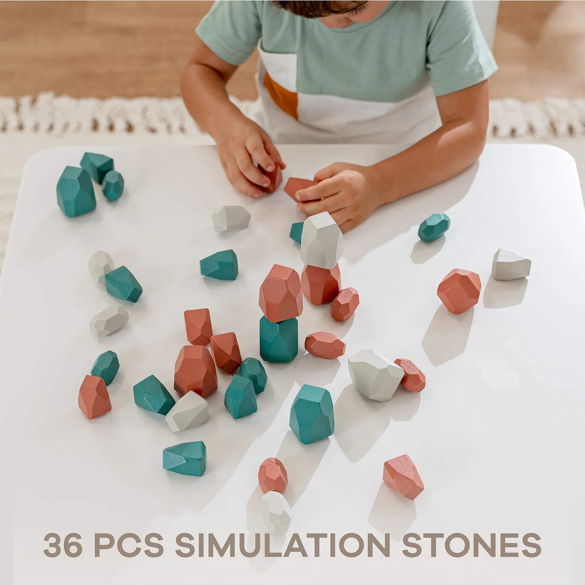 Child playing with 36-piece colorful wooden simulation stones on white table, Come see us at Awaken, Franklin, Tennessee