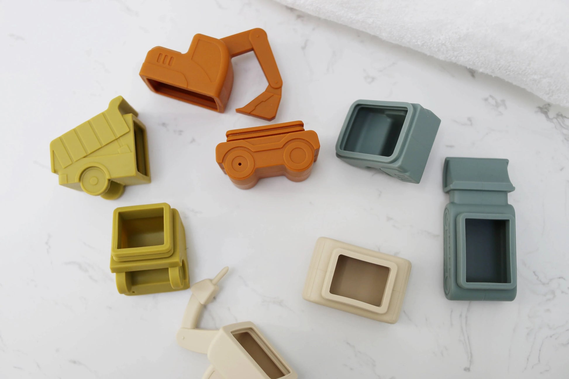 Colorful silicone construction vehicle toys on marble surface, assorted designs. Come see us at Awaken, Franklin, Tennessee