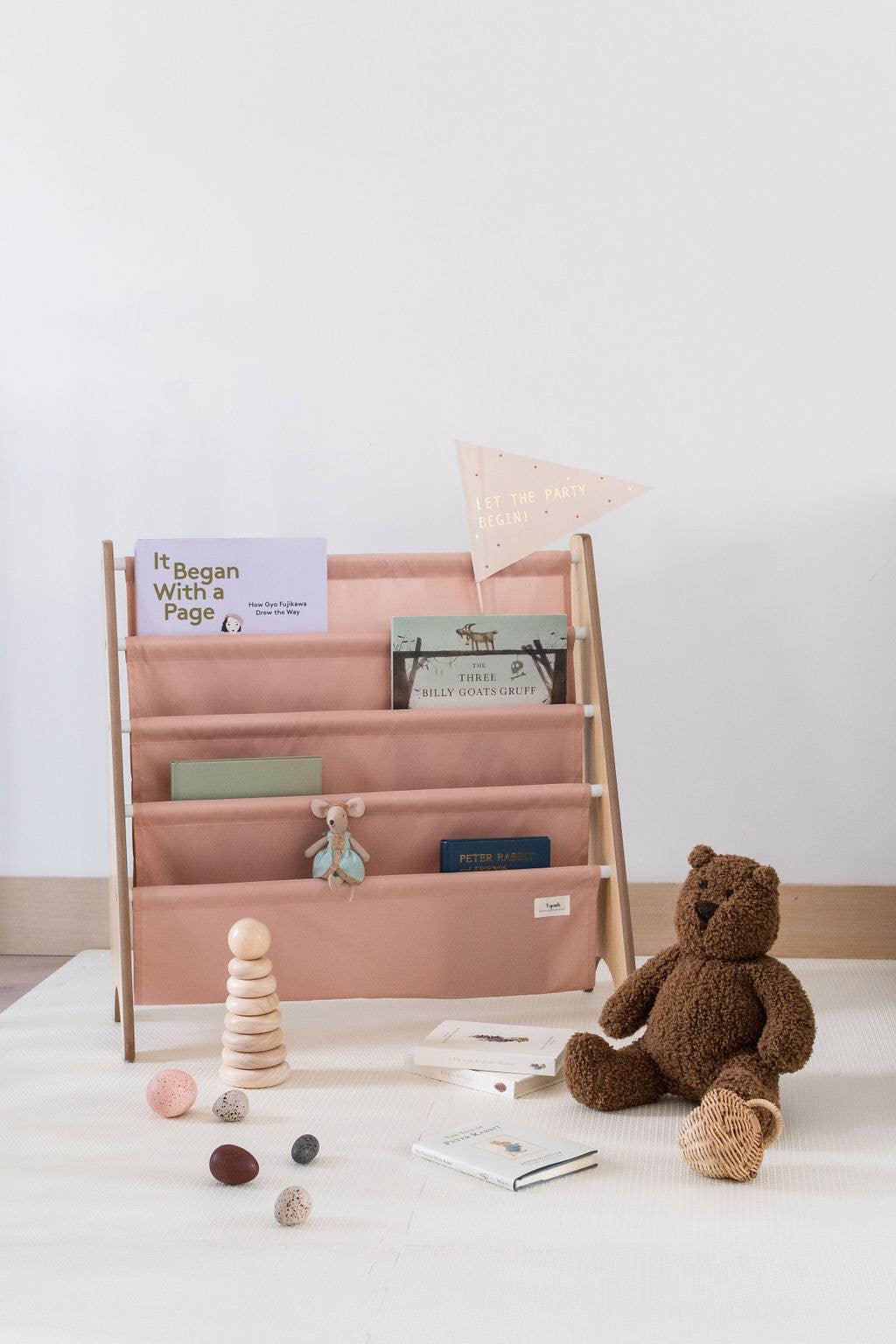 Kids' reading nook with pink book rack, plush bear, wooden stacker, Come see us at Awaken, Franklin, Tennessee