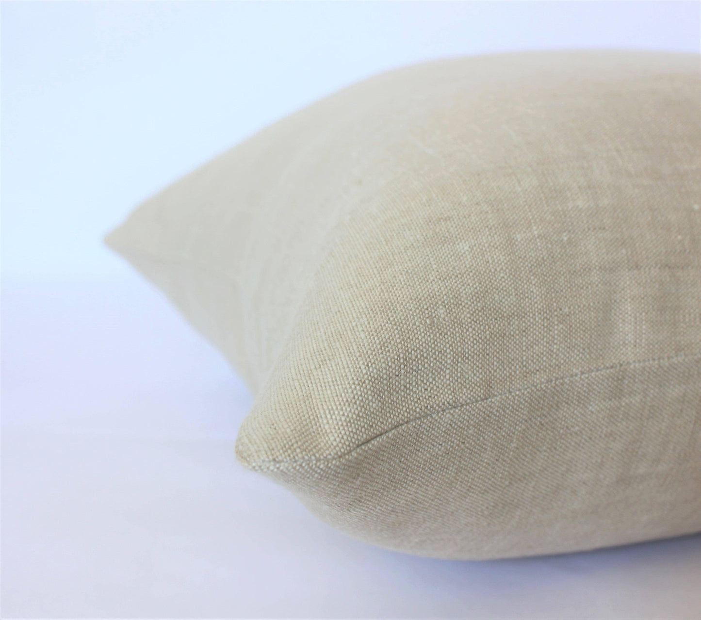 Close-up of beige linen pillow with textured fabric on white background. Come see us at Awaken, Franklin, Tennessee