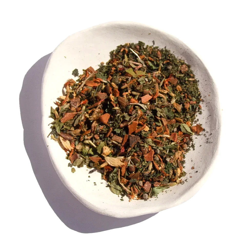 Loose dried herbal tea blend in white bowl with green and brown leaves, spices; Come see us at Awaken, Franklin, Tennessee