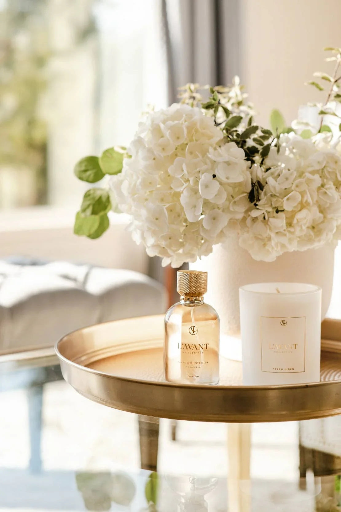 Lavant candle, fragrance bottle, and white hydrangeas on gold tray, Come see us at Awaken, Franklin, Tennessee