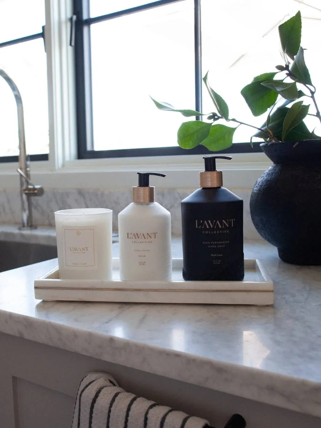 L'AVANT soap, lotion, and candle on marble kitchen counter by window, Come see us at Awaken, Franklin, Tennessee
