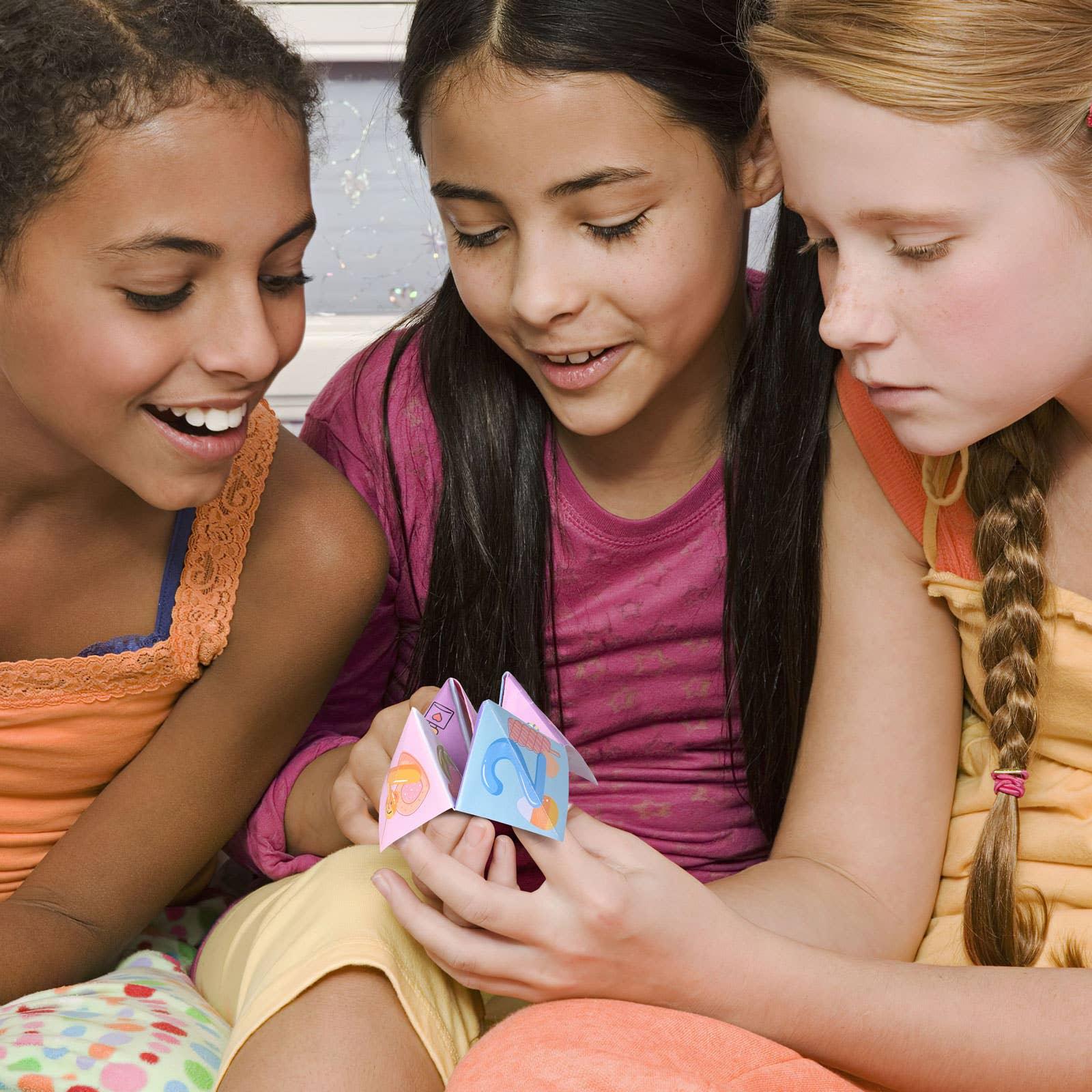 Three girls playing with a colorful paper fortune teller, Come see us at Awaken, Franklin, Tennessee