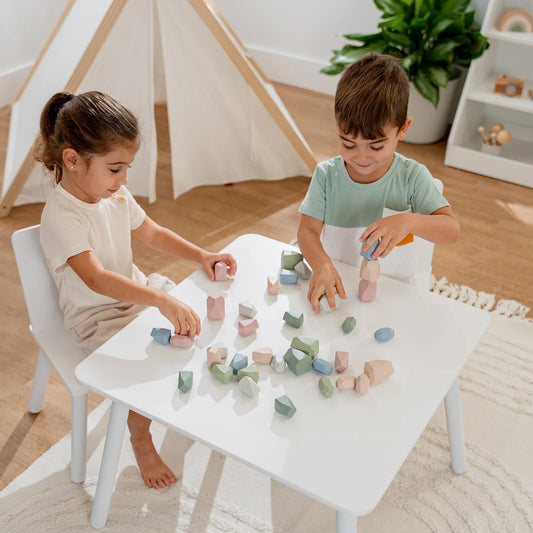 Two children playing with pastel-colored wooden blocks at white table in bright room. Come see us at Awaken, Franklin, Tennessee