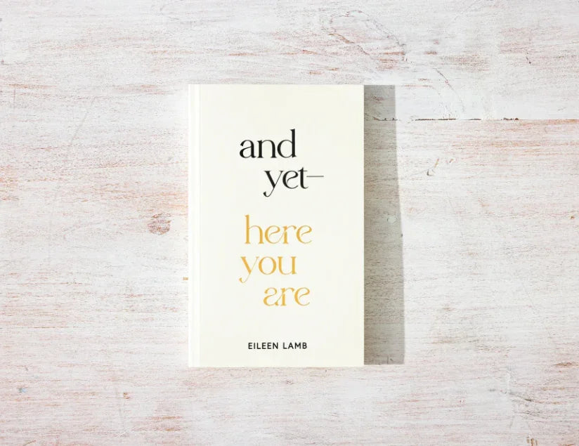 Book titled 'and yet—here you are' by Eileen Lamb on a light wooden surface. Come see us at Awaken, Franklin, Tennessee