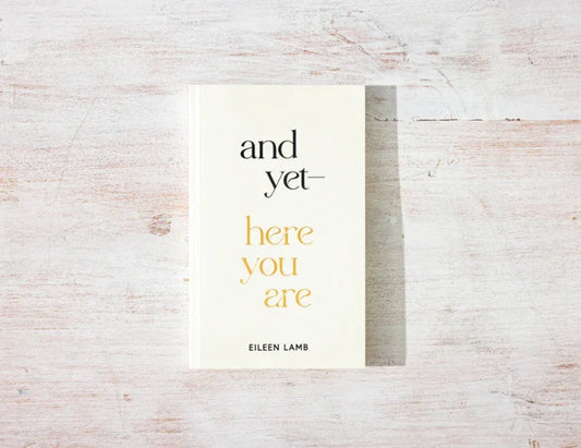 Book titled 'and yet—here you are' by Eileen Lamb on a light wooden surface. Come see us at Awaken, Franklin, Tennessee