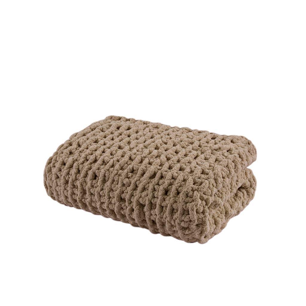 Folded chunky knit beige blanket with soft texture on white background. Come see us at Awaken, Franklin, Tennessee
