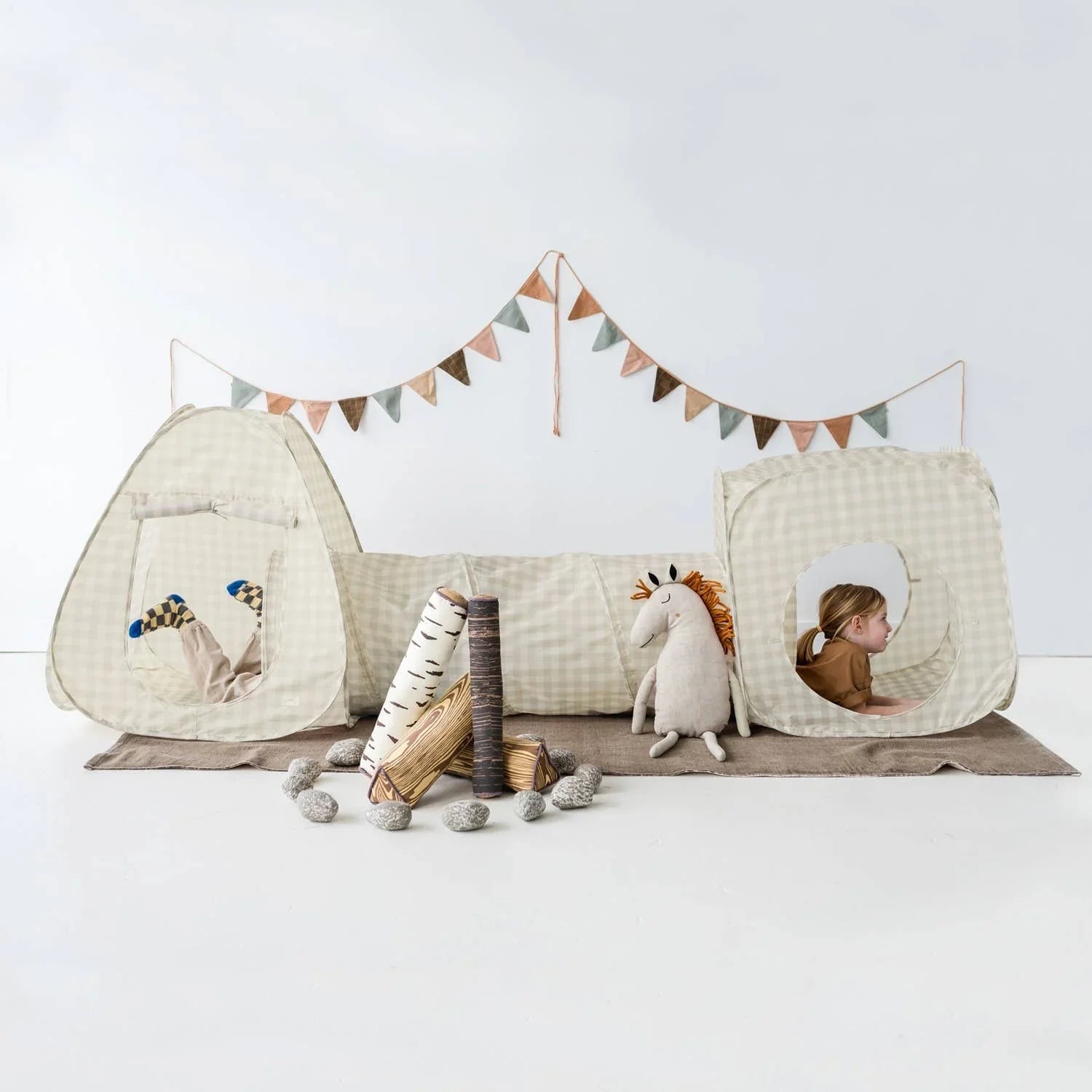 Kids playing in beige check tent tunnel with plush unicorn and faux campfire inside room Come see us at Awaken, Franklin, Tennessee