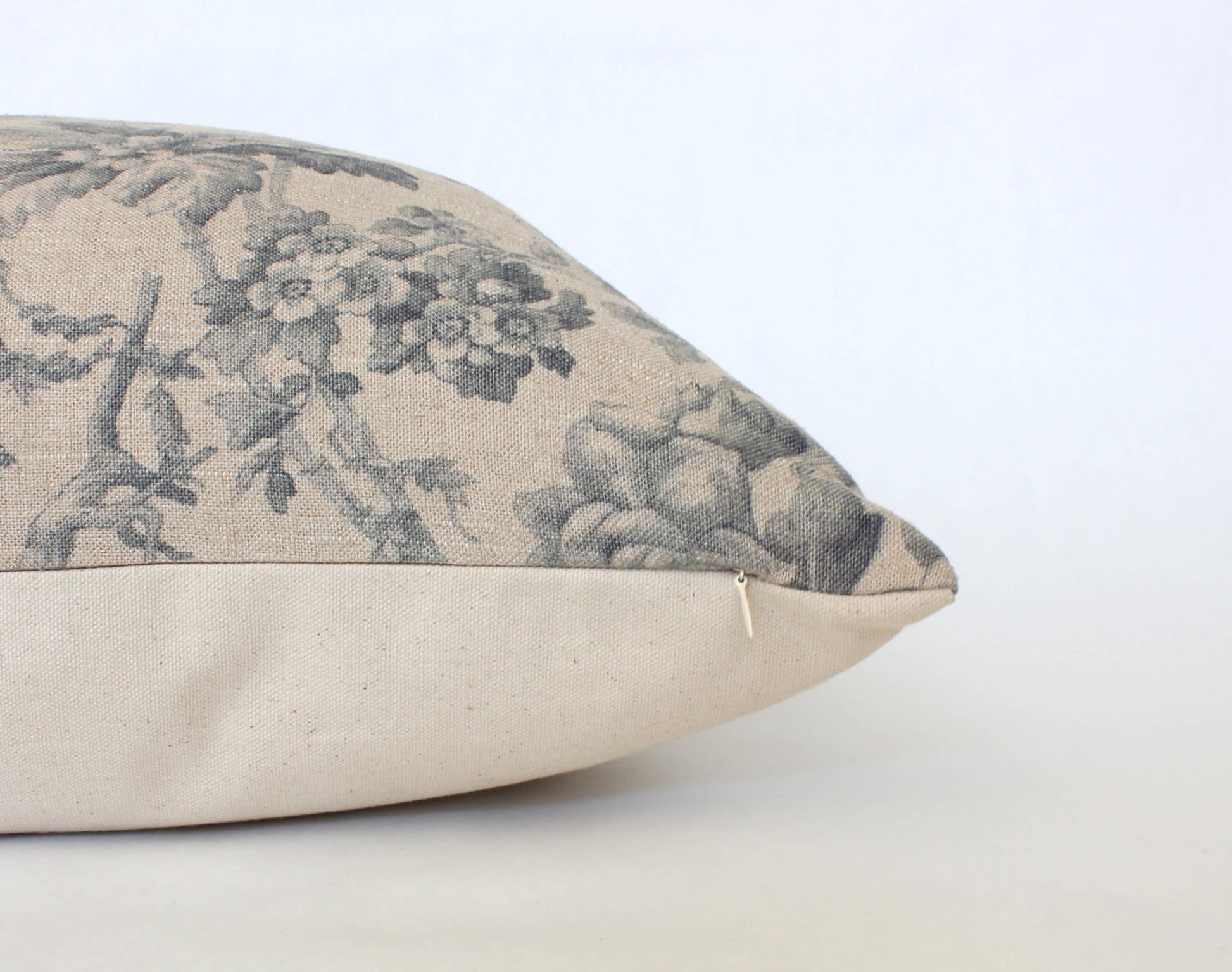 Decorative beige pillow with vintage floral print and zipper detail on white background. Come see us at Awaken, Franklin, Tennessee