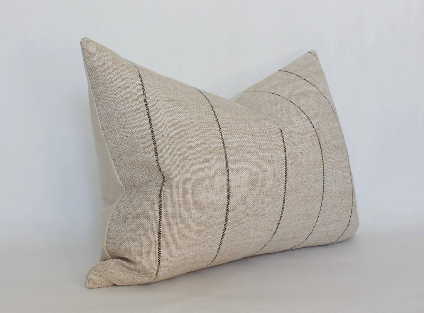 Natural beige lumbar pillow with subtle black stripes on white background. Come see us at Awaken, Franklin, Tennessee