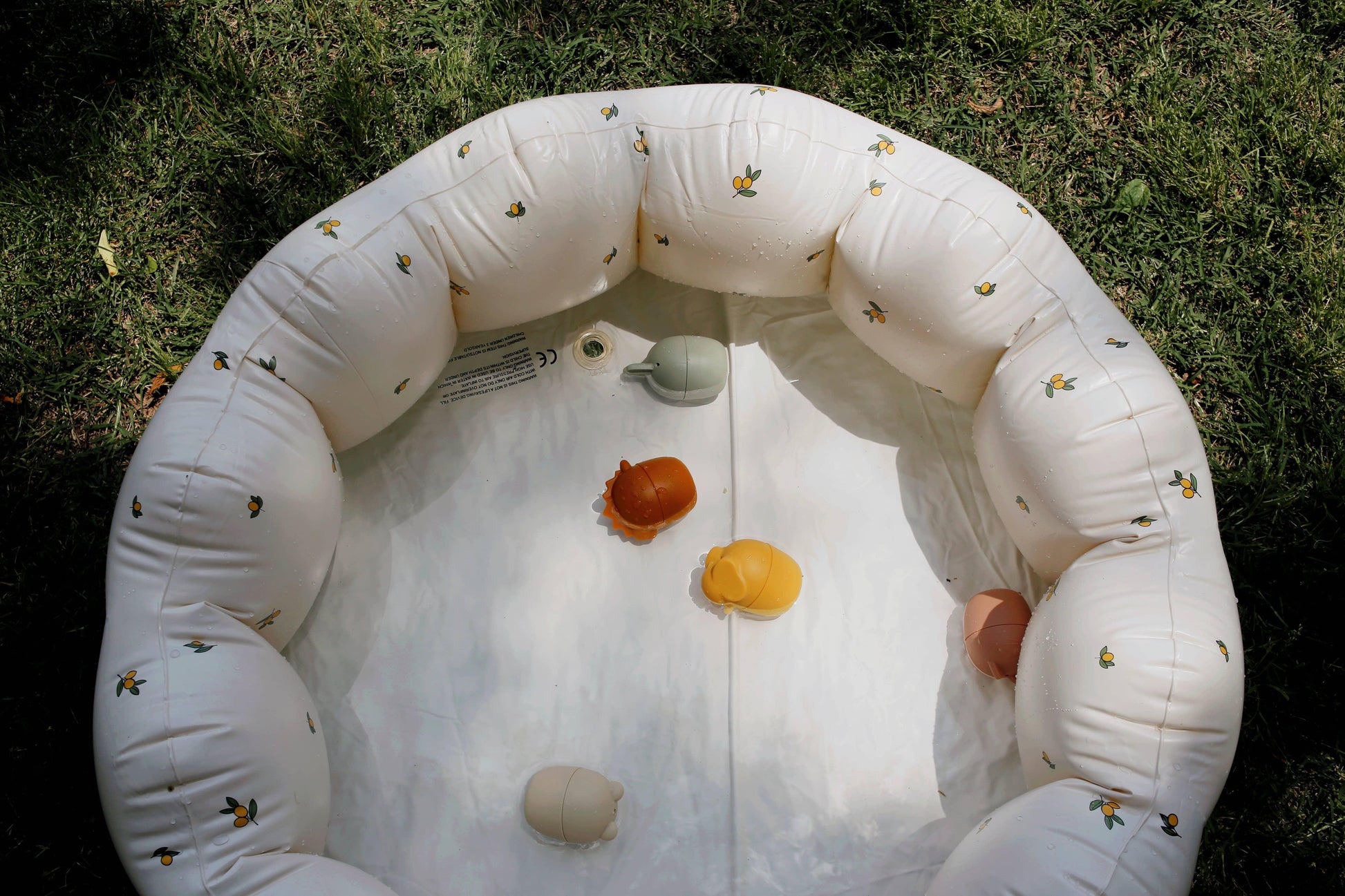 Inflatable white kiddie pool with small colorful toys on grass, come see us at Awaken, Franklin, Tennessee