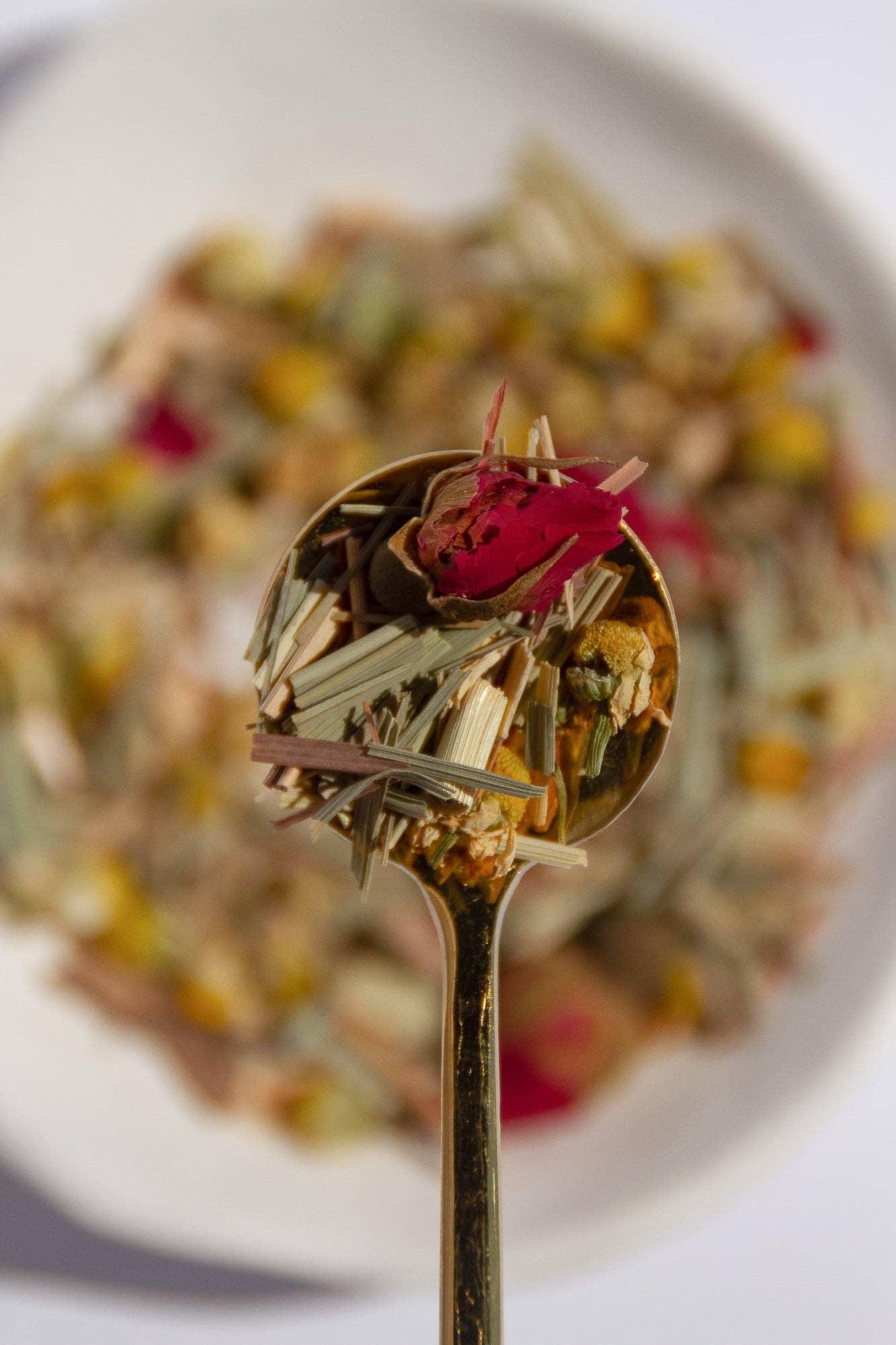 Spoonful of loose herbal tea blend with dried flowers and lemongrass on white plate, come see us at Awaken, Franklin, Tennessee