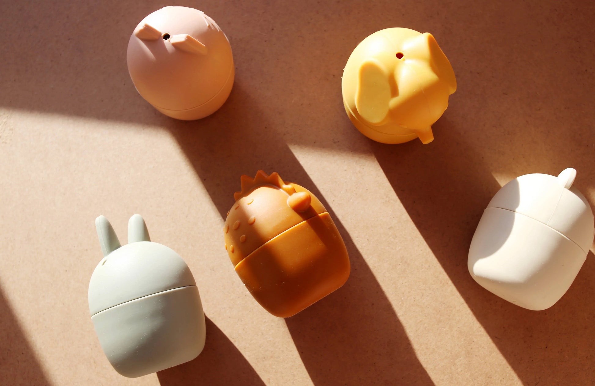 Five animal-shaped silicone containers casting shadows on a surface in natural light. Come see us at Awaken, Franklin, Tennessee