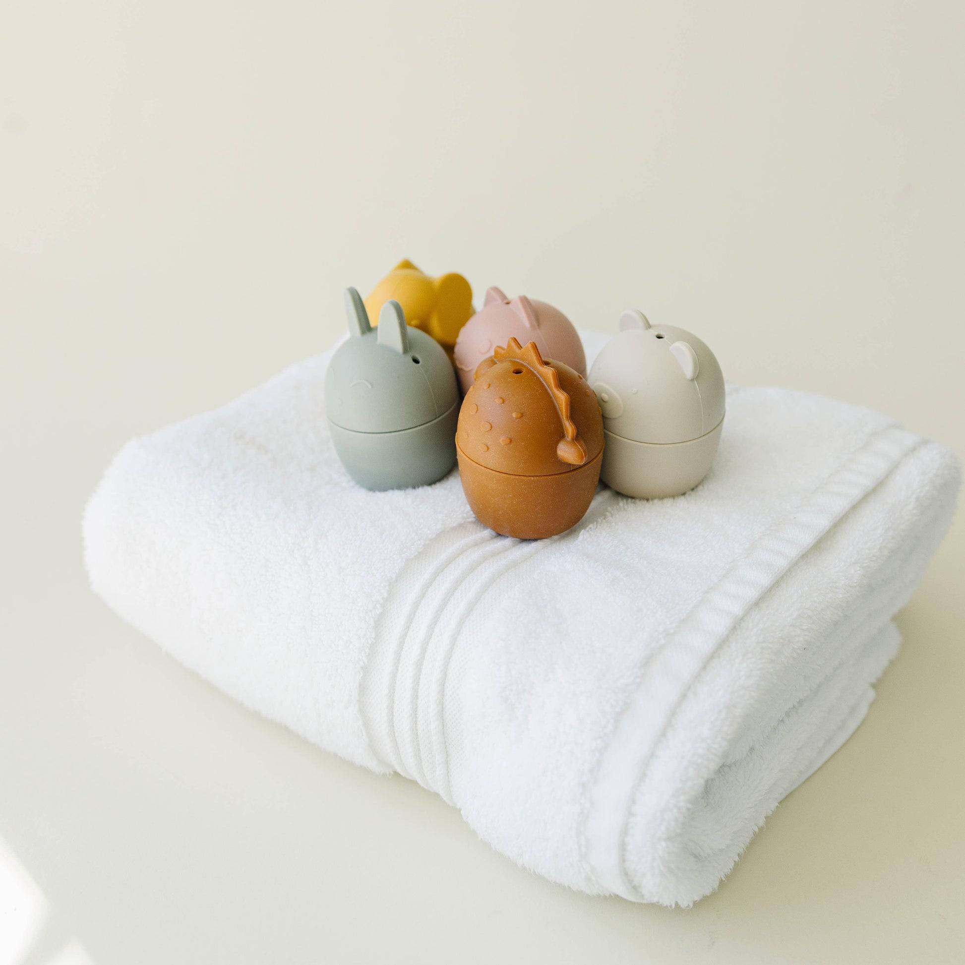 Cute animal-themed bath toys displayed on a neatly folded white towel Come see us at Awaken, Franklin, Tennessee