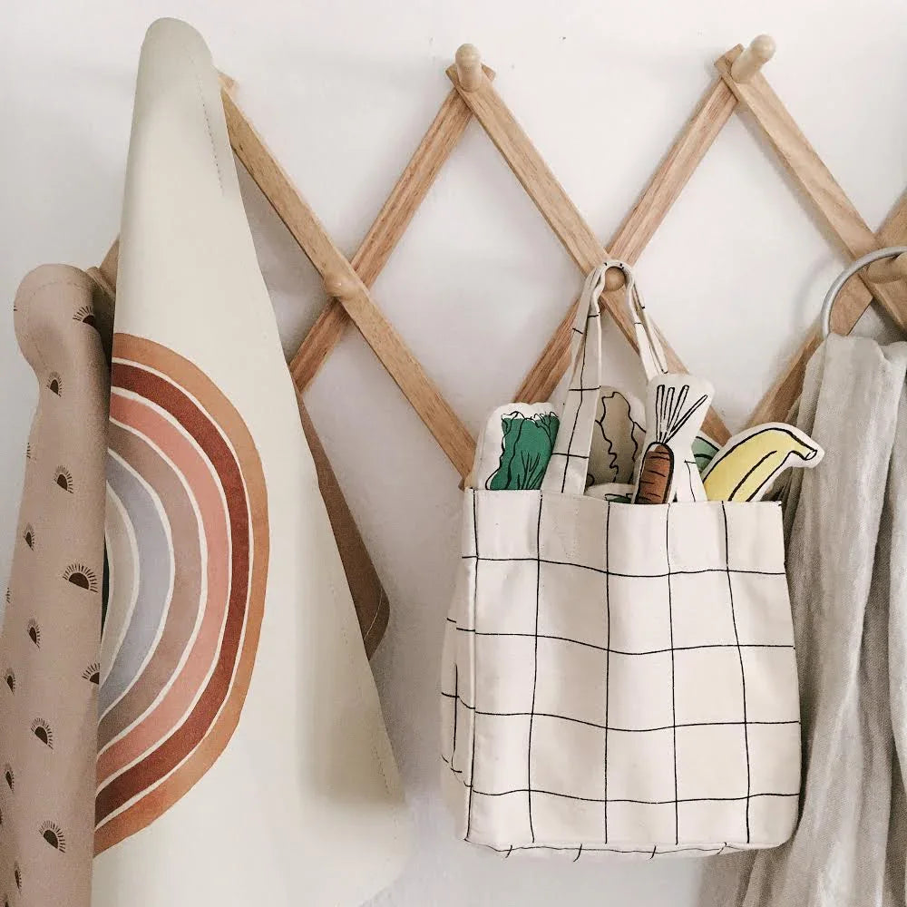 Grid tote bag with toy vegetables on wooden rack, neutral decor. Come see us at Awaken, Franklin, Tennessee.