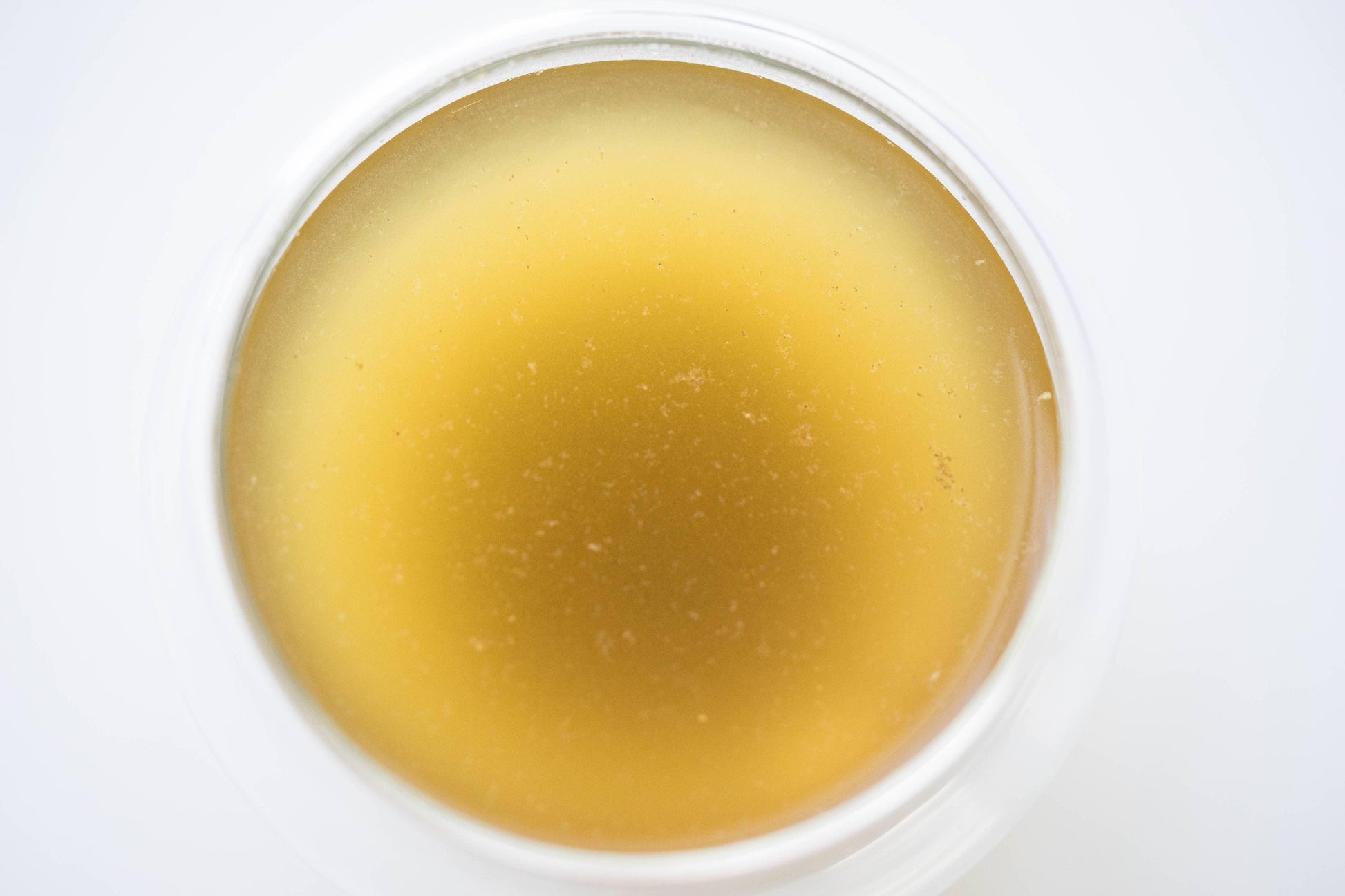 Close-up of translucent golden wax balm in a clear round container, Come see us at Awaken, Franklin, Tennessee