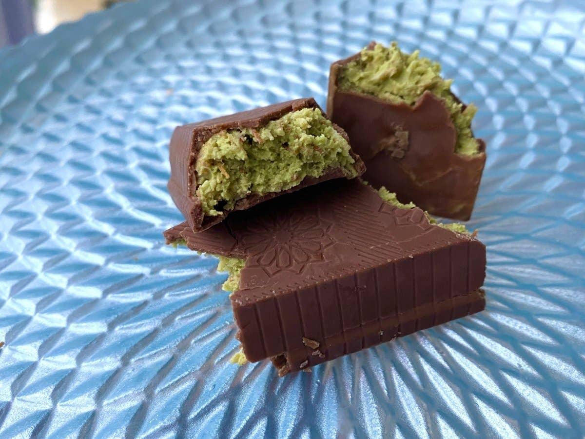 Chocolate pieces with green matcha filling on textured blue plate. Come see us at Awaken, Franklin, Tennessee