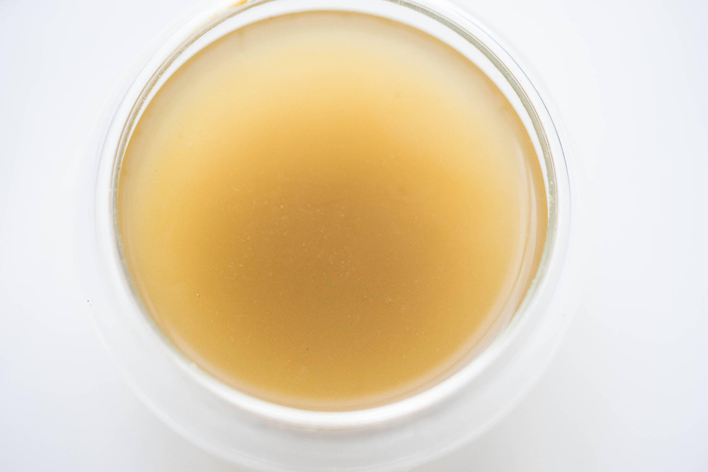 Close-up of light brown herbal tea in clear glass cup on white background. Come see us at Awaken, Franklin, Tennessee