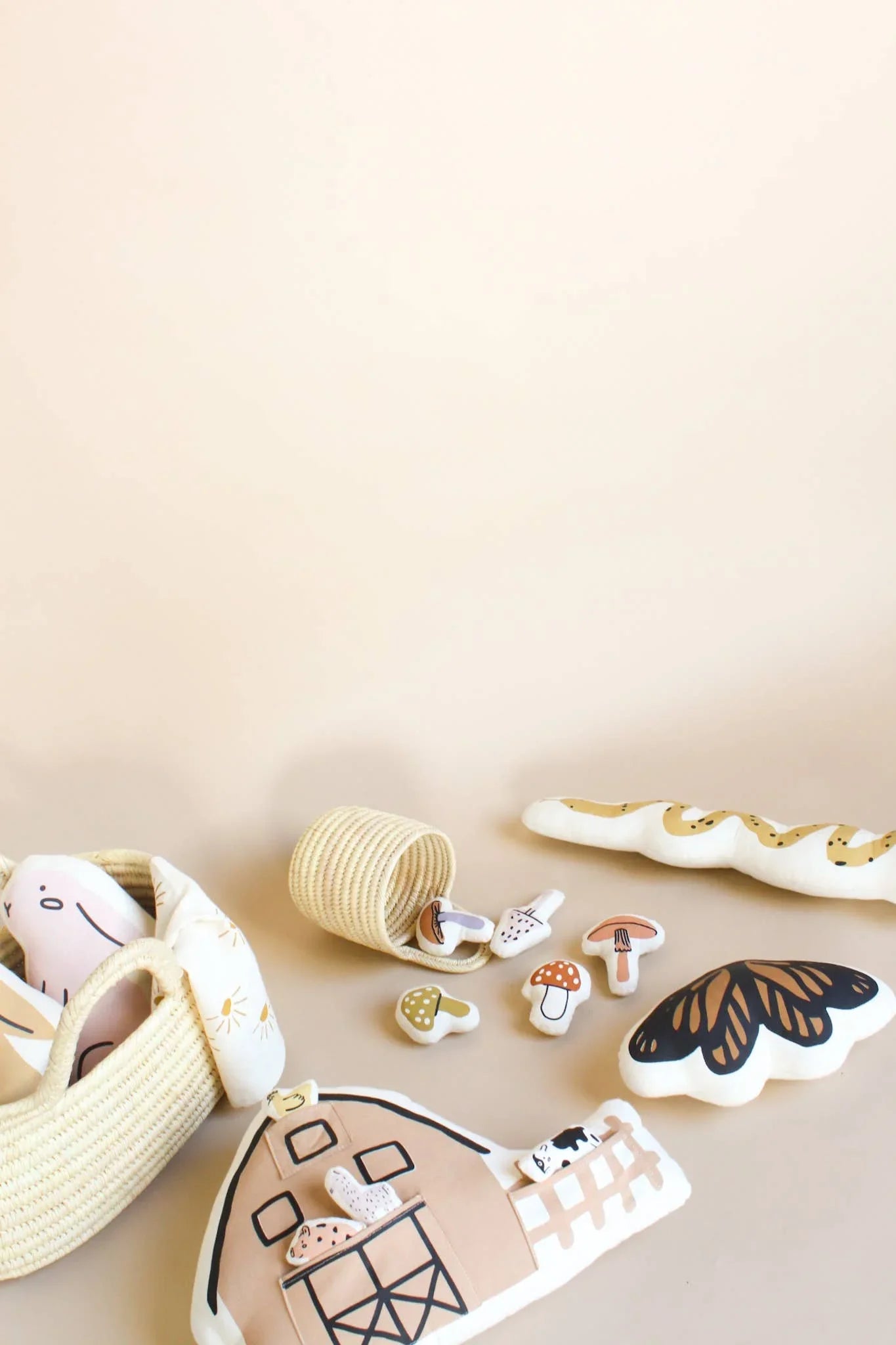 Plush barn toys, mushrooms, butterfly, and basket on beige background. Come see us at Awaken, Franklin, Tennessee.