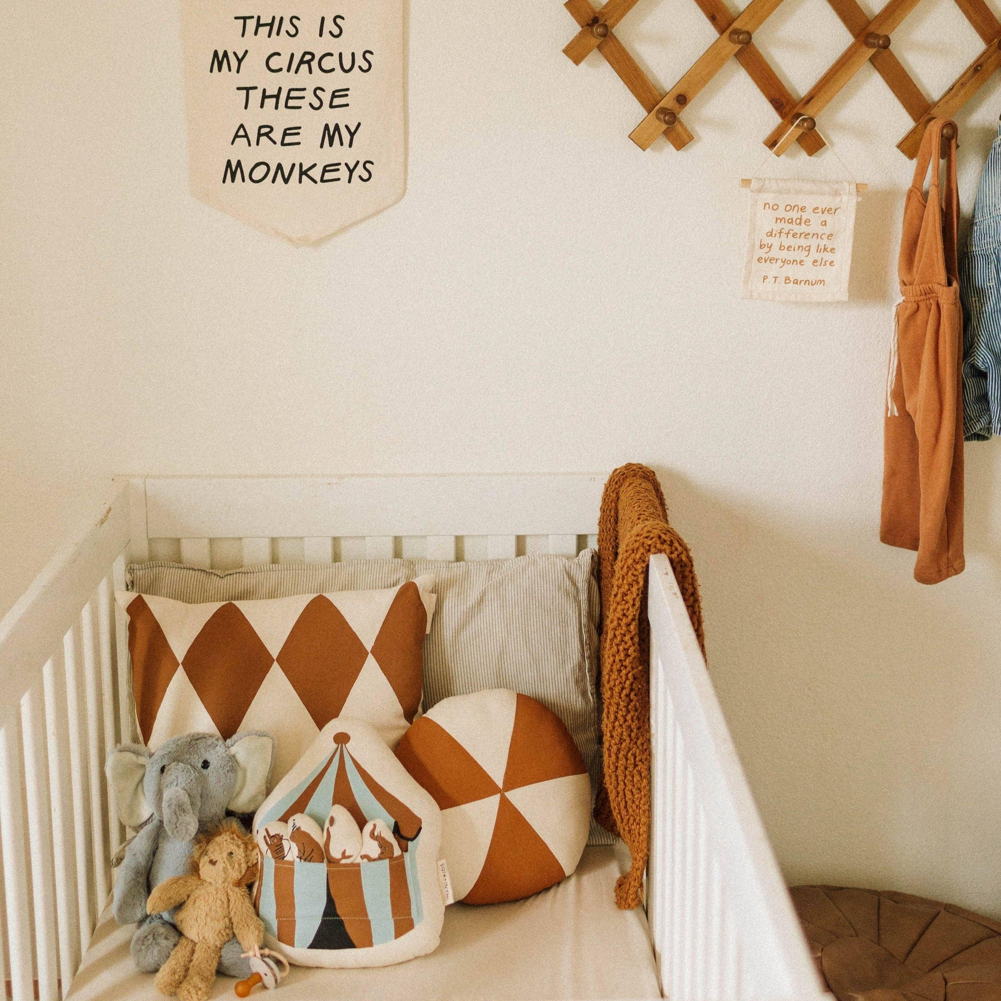 Neutral nursery with circus pillows, stuffed animals, and playful wall decor. Come see us at Awaken, Franklin, Tennessee.