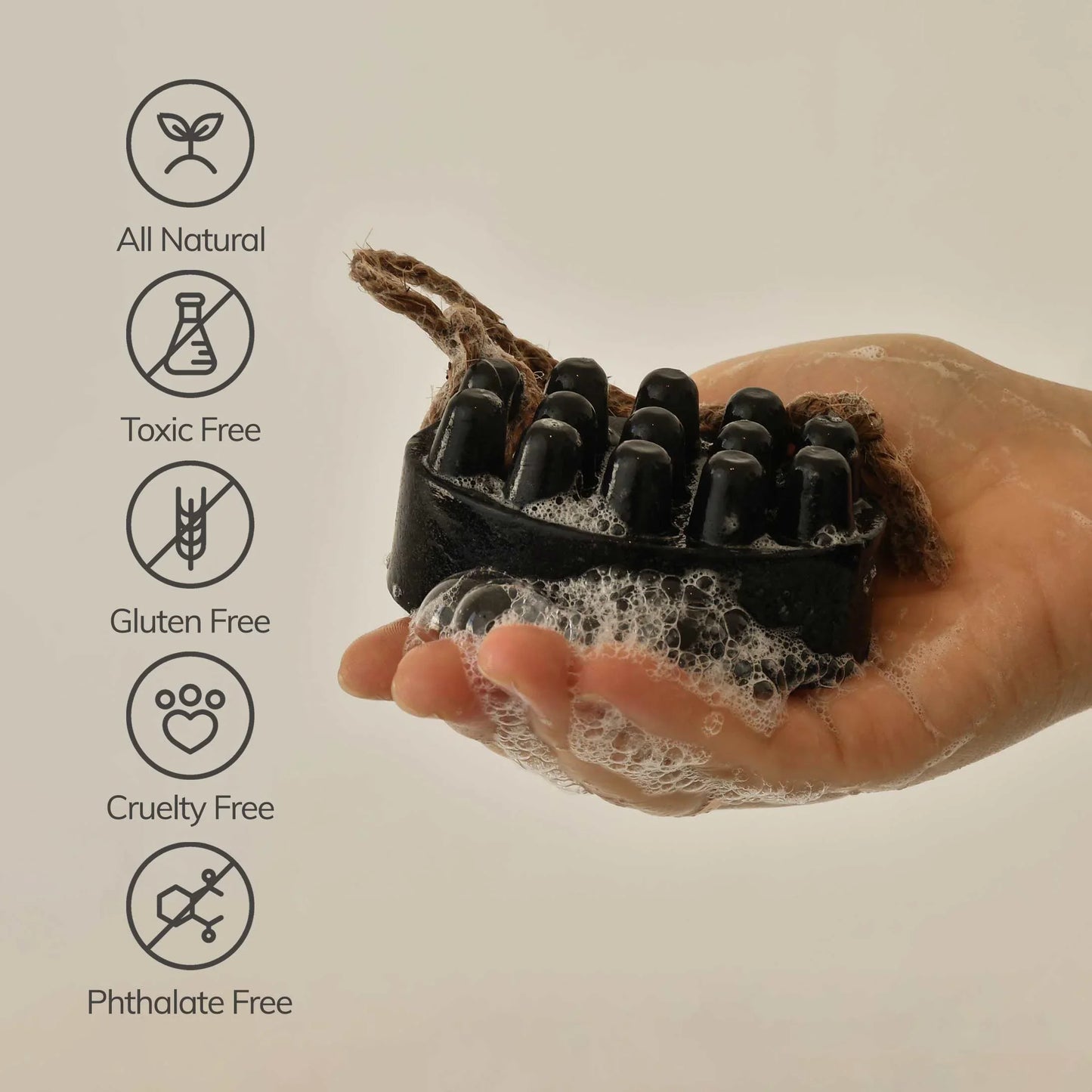 Hand holding a black soapy scrub brush with rope handle, labeled all natural, toxic free, gluten free, cruelty free, phthalate free. Come see us at Awaken, Franklin, Tennessee