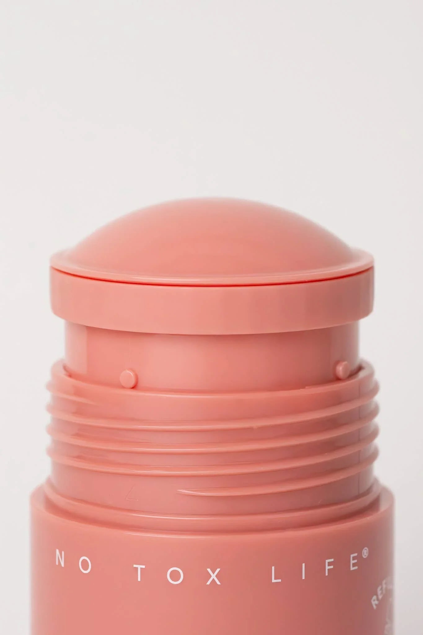 Close-up of No Tox Life skincare stick in peach tone on white background. Come see us at Awaken, Franklin, Tennessee