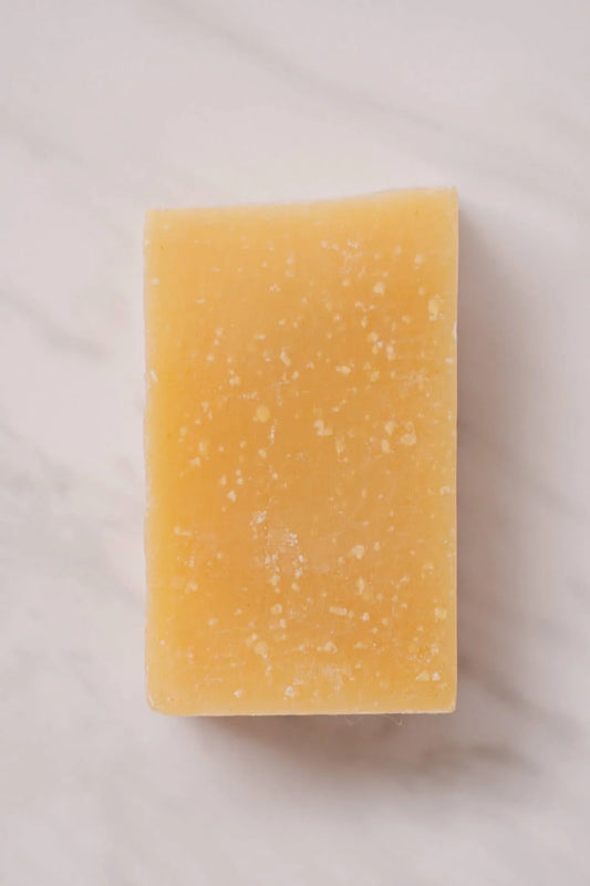 Rectangular yellow bar of natural soap on white marble surface. Come see us at Awaken, Franklin, Tennessee