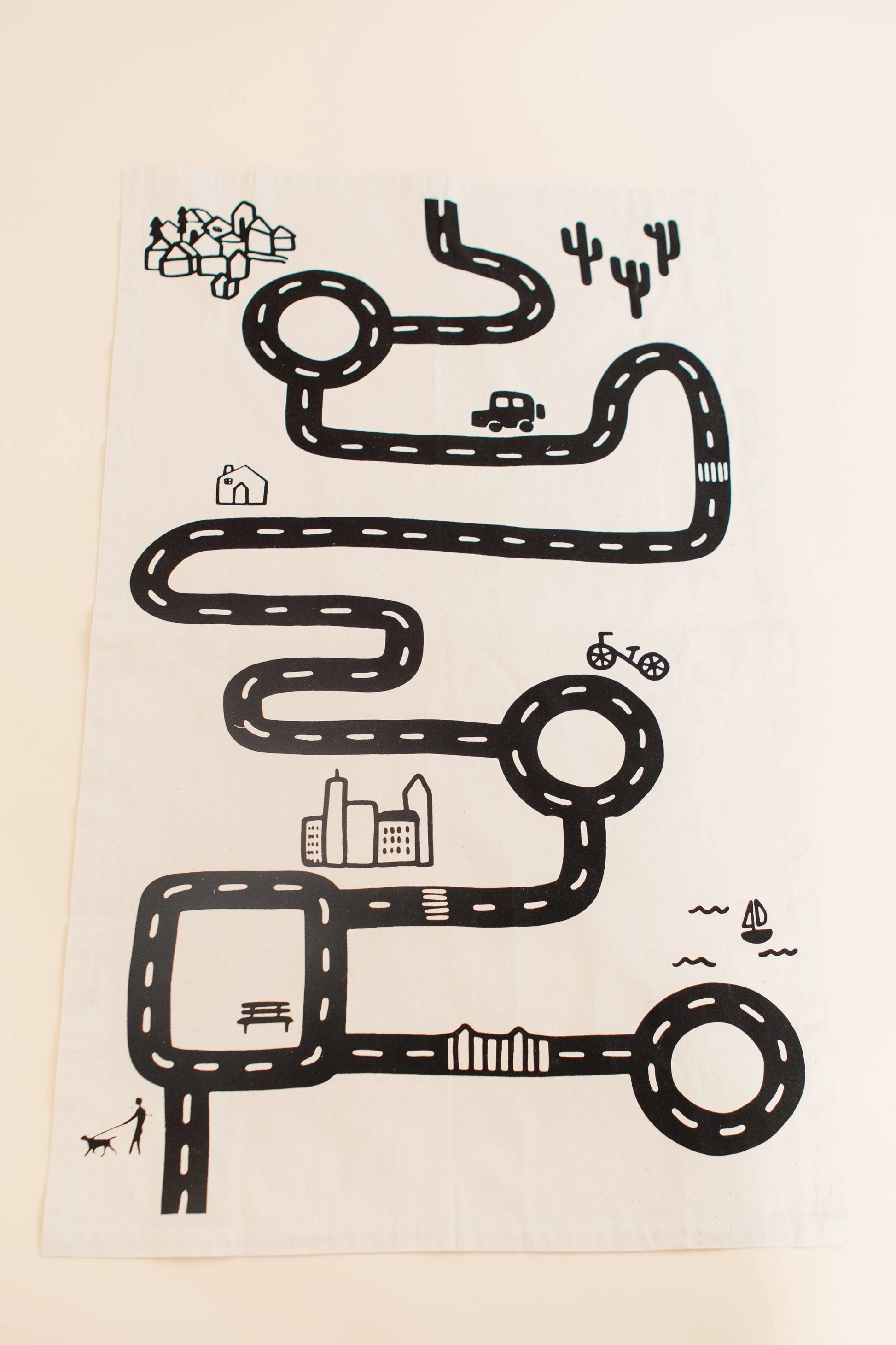 Kids playmat with black road, car, bike, city, park, and boat. Come see us at Awaken, Franklin, Tennessee