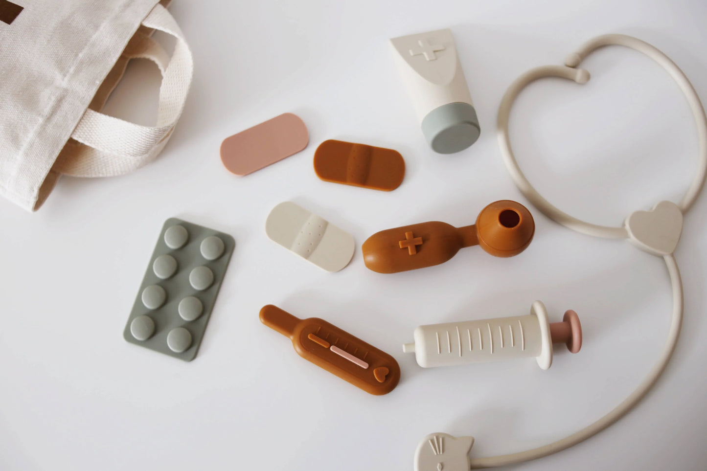 Child's toy medical kit with bandages, syringe, thermometer, and stethoscope on white surface. Come see us at Awaken, Franklin, Tennessee