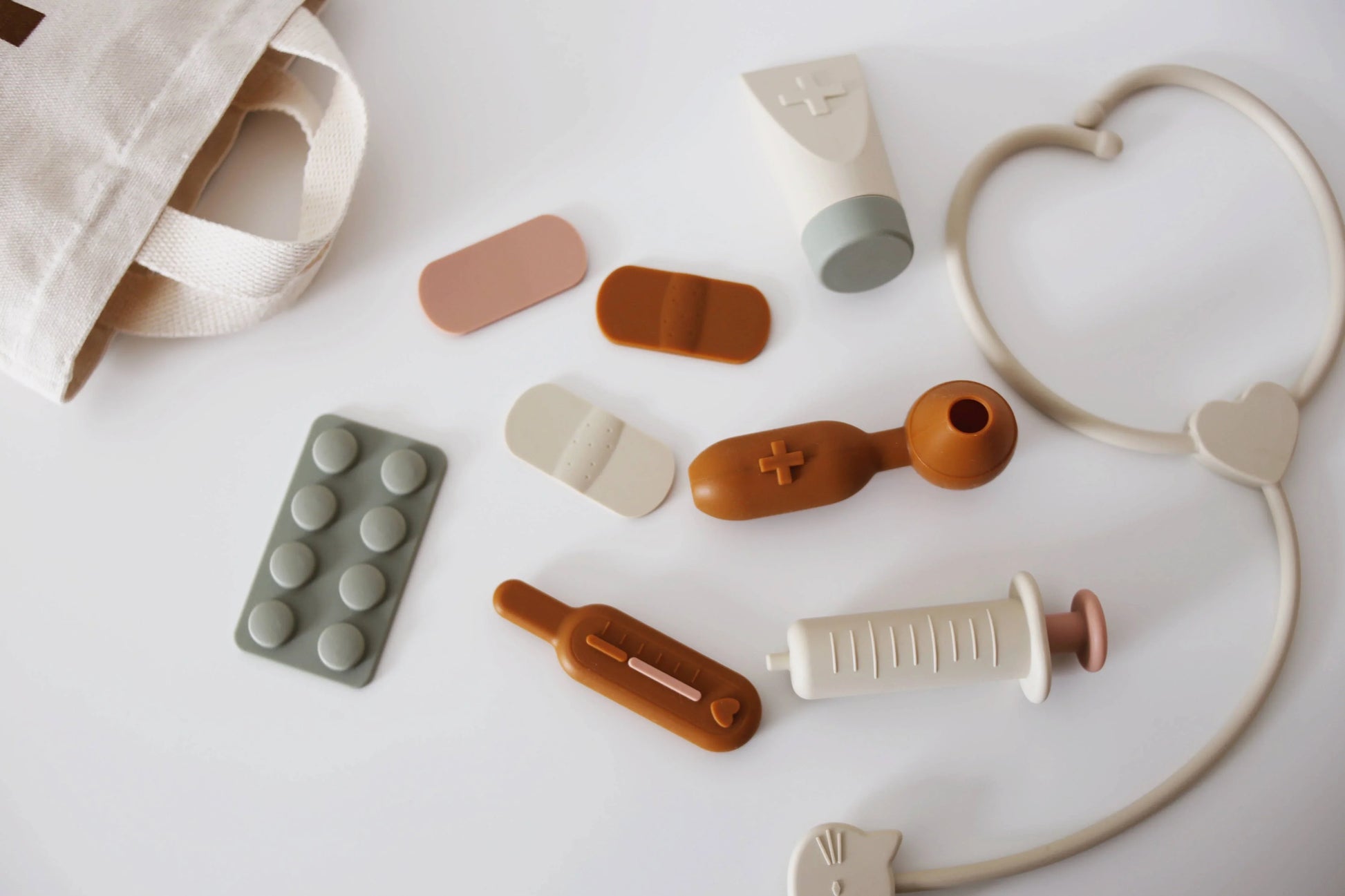 Child's toy medical kit with bandages, syringe, thermometer, and stethoscope on white surface. Come see us at Awaken, Franklin, Tennessee