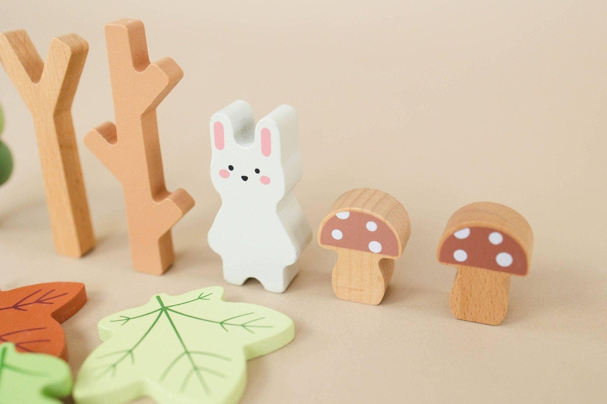 Wooden toy set with white bunny, mushrooms, trees, and leaves on beige background. Come see us at Awaken, Franklin, Tennessee