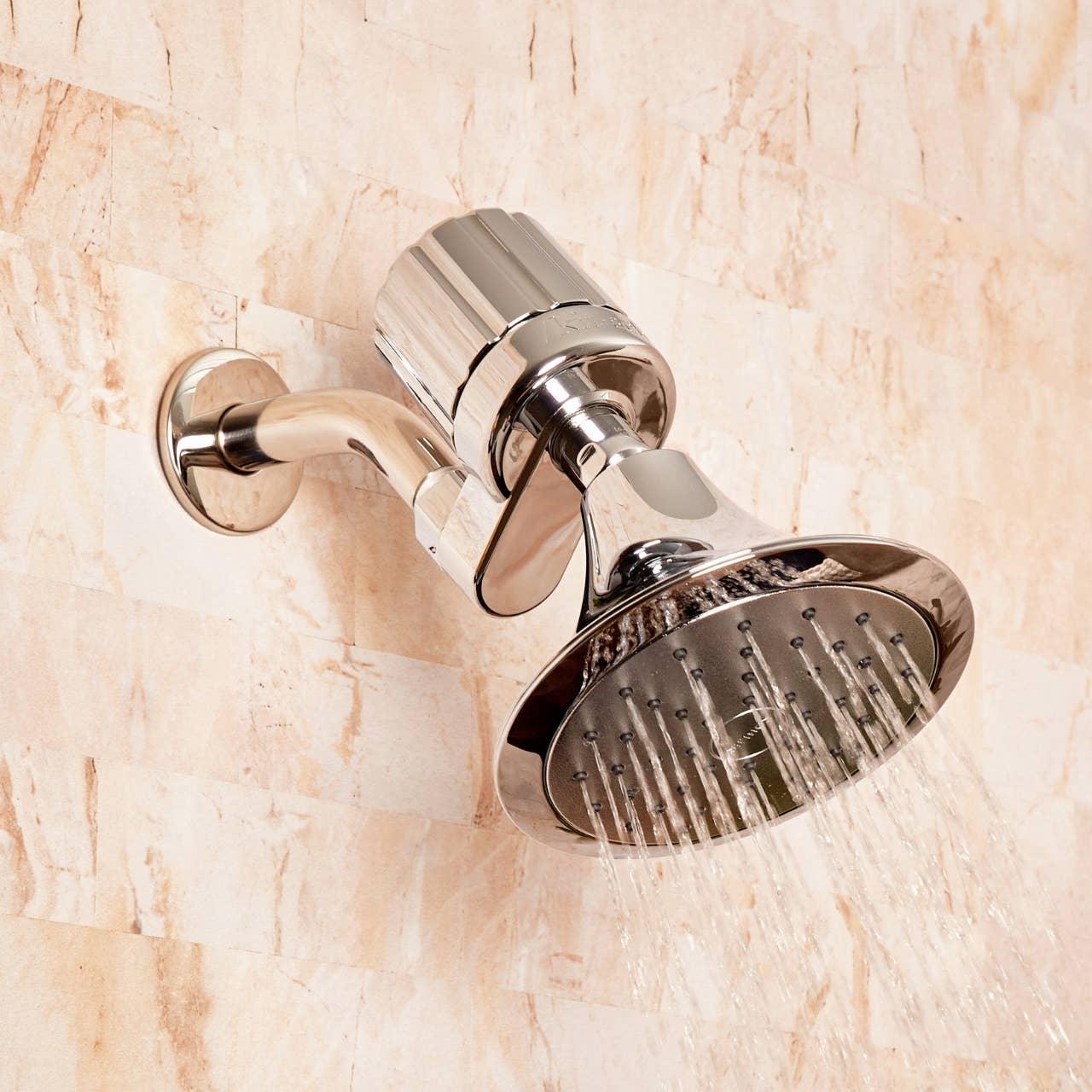 Chrome shower head with running water on beige tile wall, Come see us at Awaken, Franklin, Tennessee