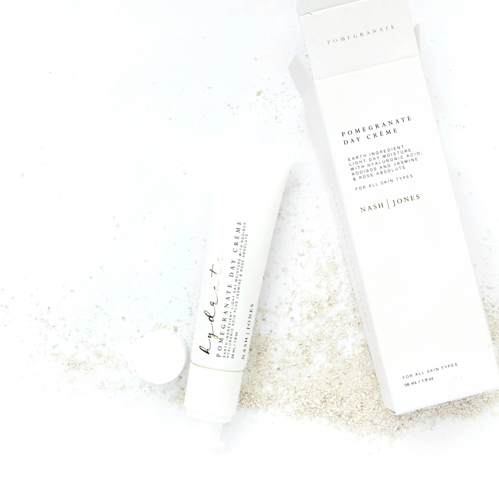 Nash | Jones Pomegranate Day Crème tube and box on white background with natural powder. Come see us at Awaken, Franklin, Tennessee