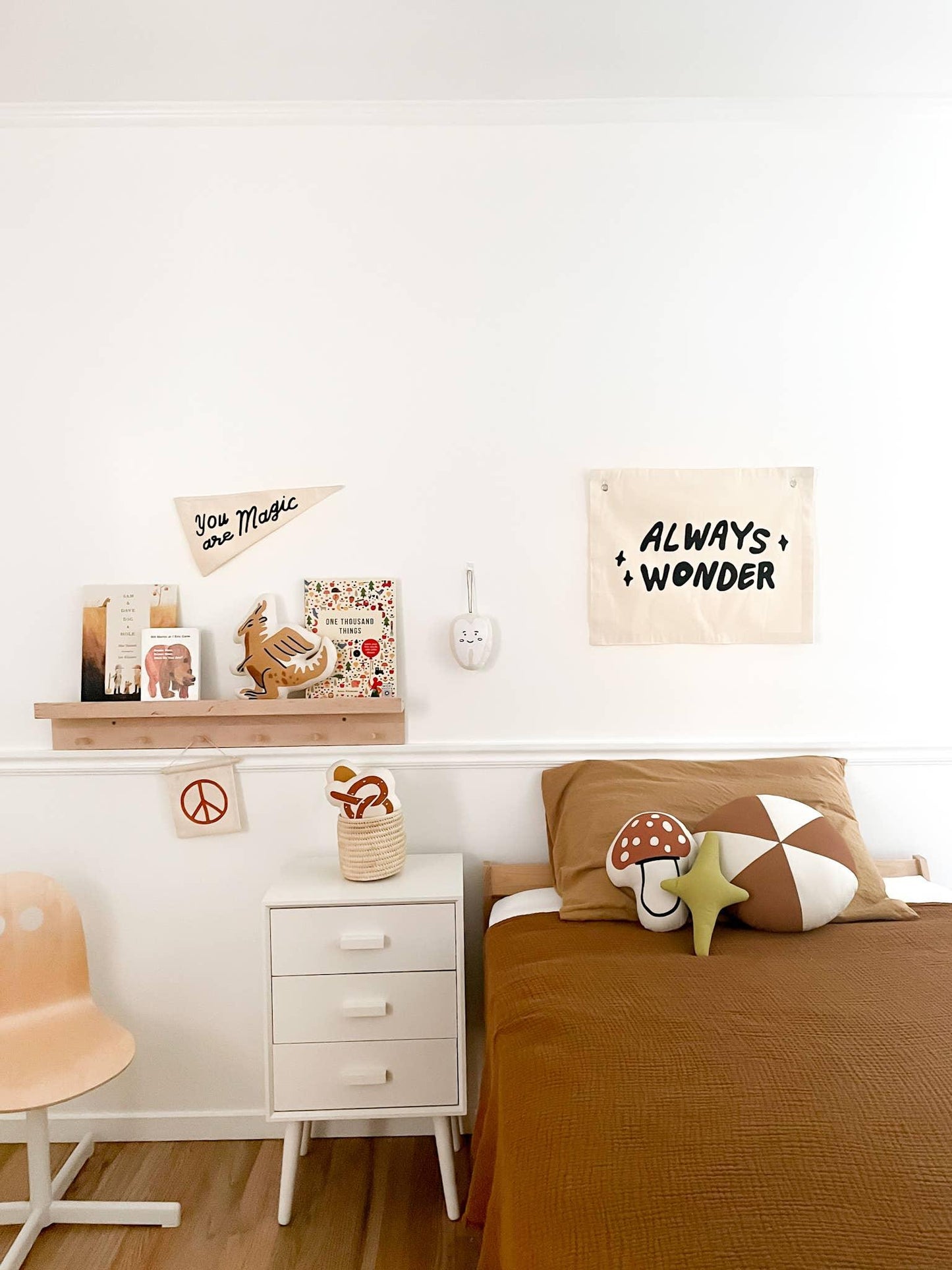 Cozy kids bedroom with brown bedding, playful pillows, wall art, and shelf decor, Come see us at Awaken, Franklin, Tennessee