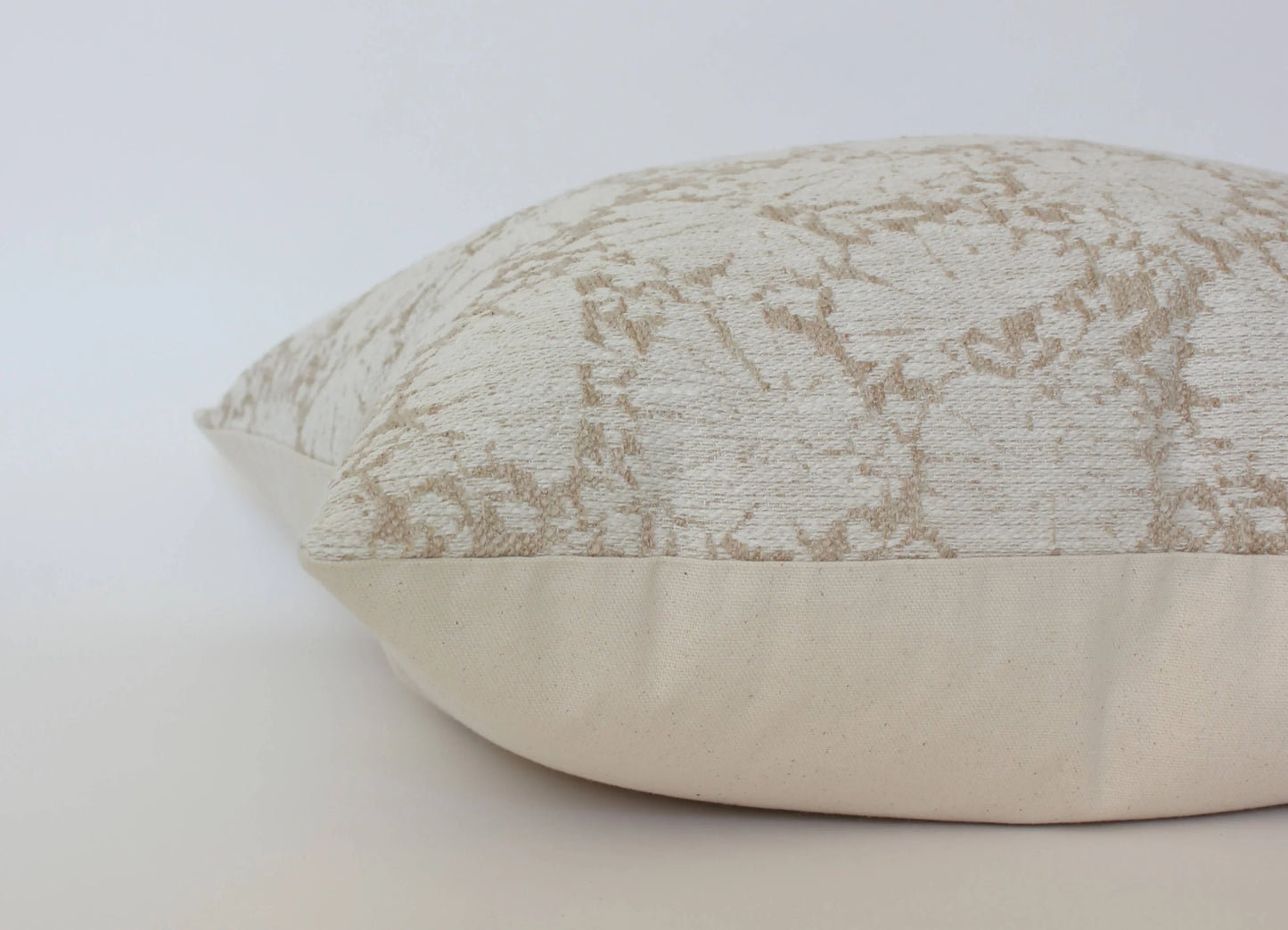 Beige decorative pillow with abstract pattern on white background. Come see us at Awaken, Franklin, Tennessee