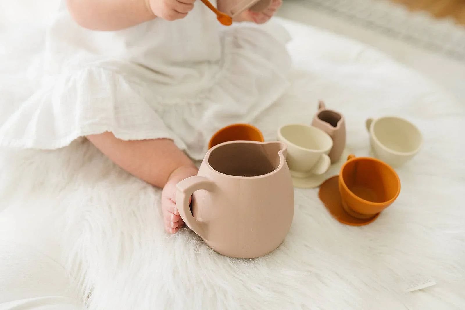 Baby playing with ceramic tea set on white blanket, Come see us at Awaken, Franklin, Tennessee