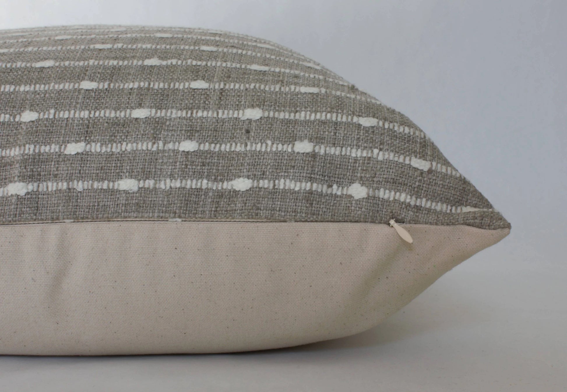 Textured gray and white decorative pillow on plain background. Come see us at Awaken, Franklin, Tennessee