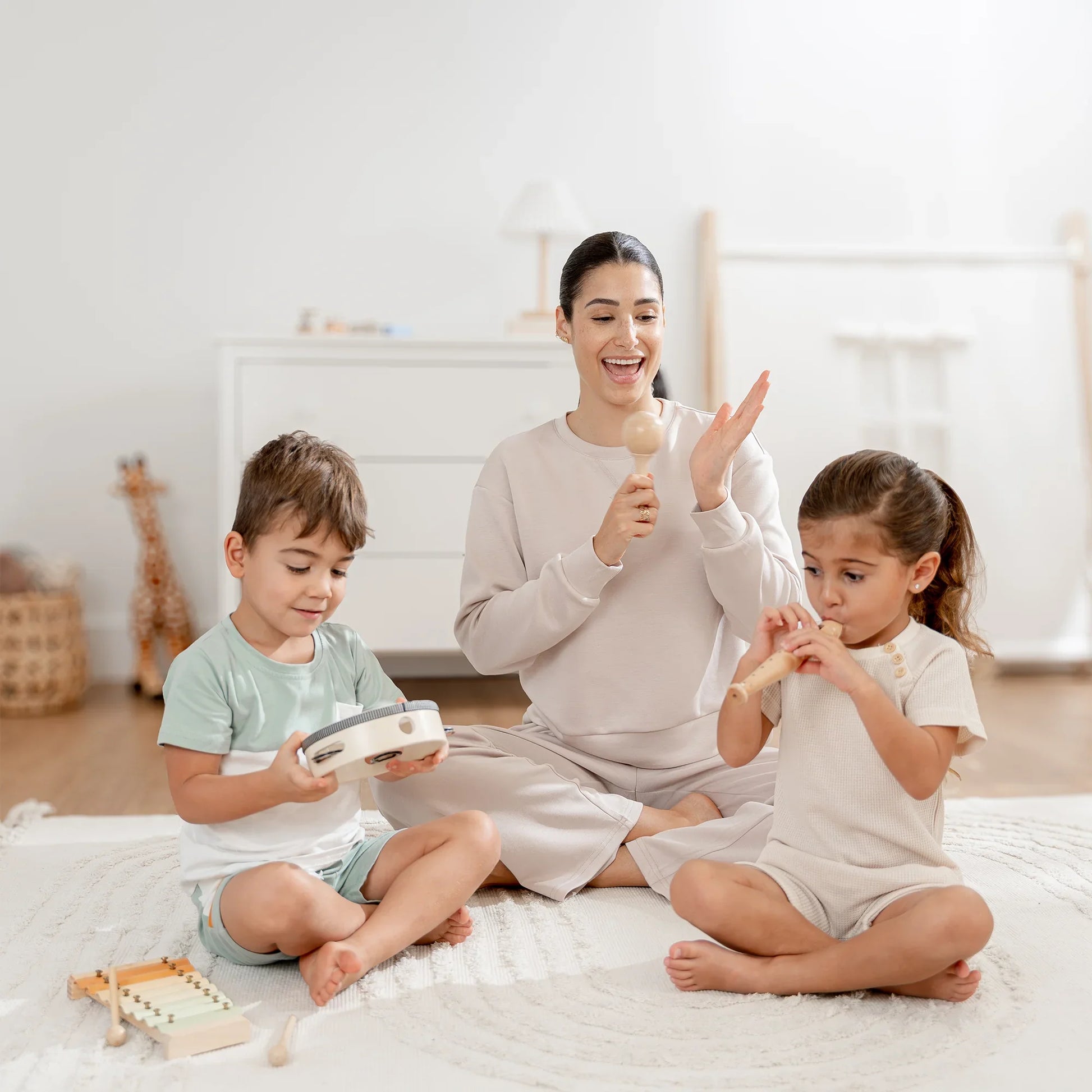 Mother and two kids playing musical instruments on a rug, Come see us at Awaken, Franklin, Tennessee.