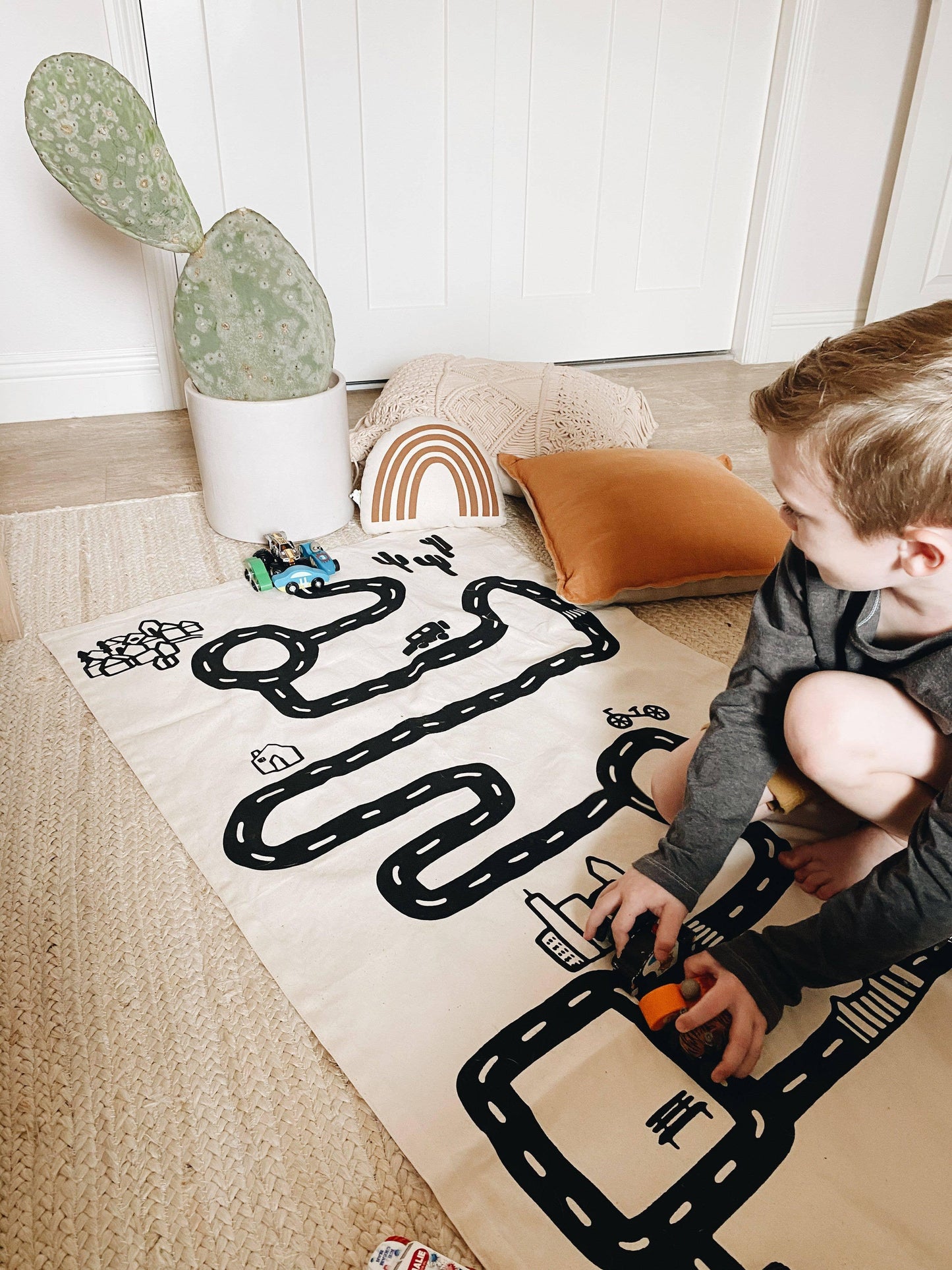 Boy playing with toy cars on a road play mat, cactus in pot, cozy pillows, Come see us at Awaken, Franklin, Tennessee