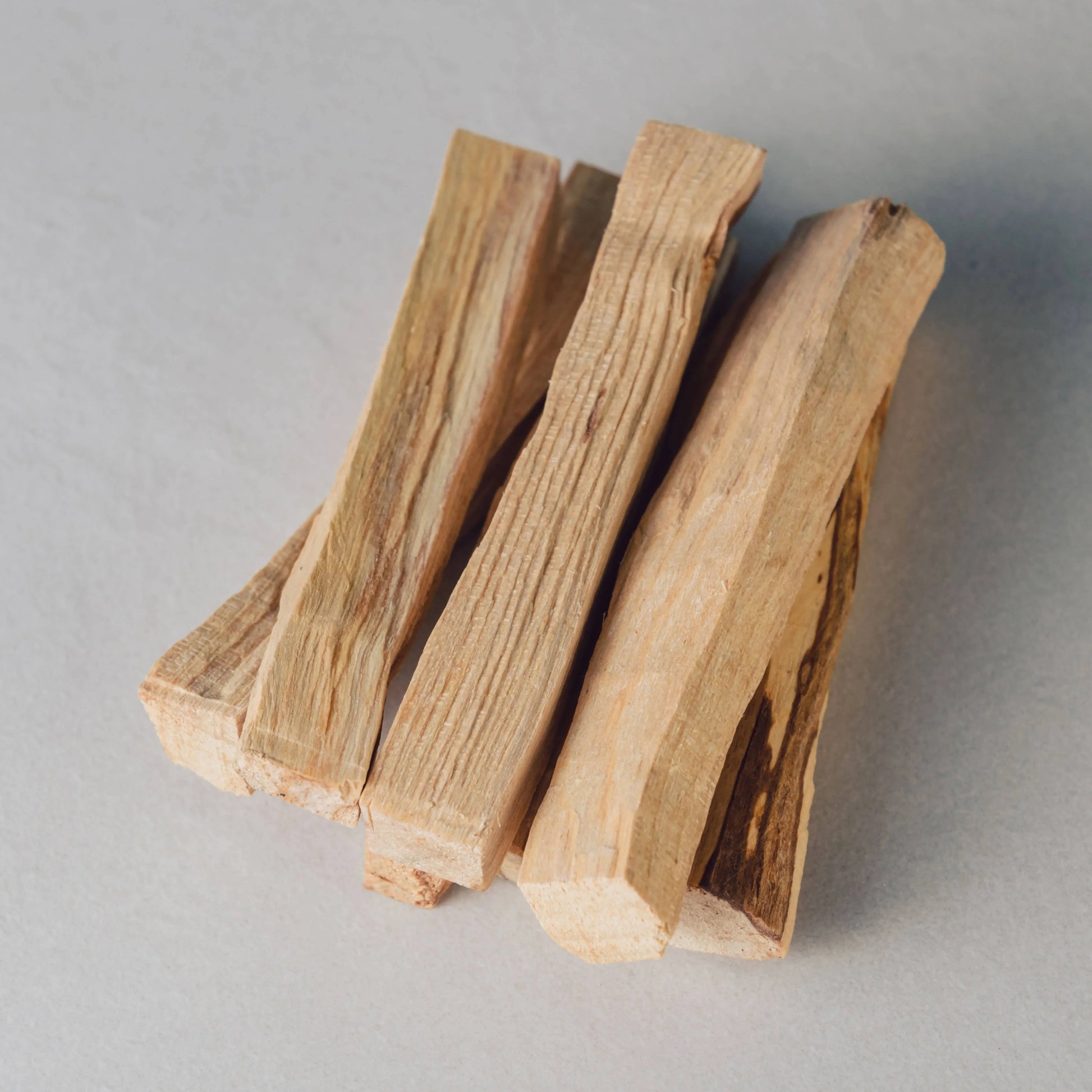 Stack of natural palo santo wood sticks on gray surface. Come see us at Awaken, Franklin, Tennessee