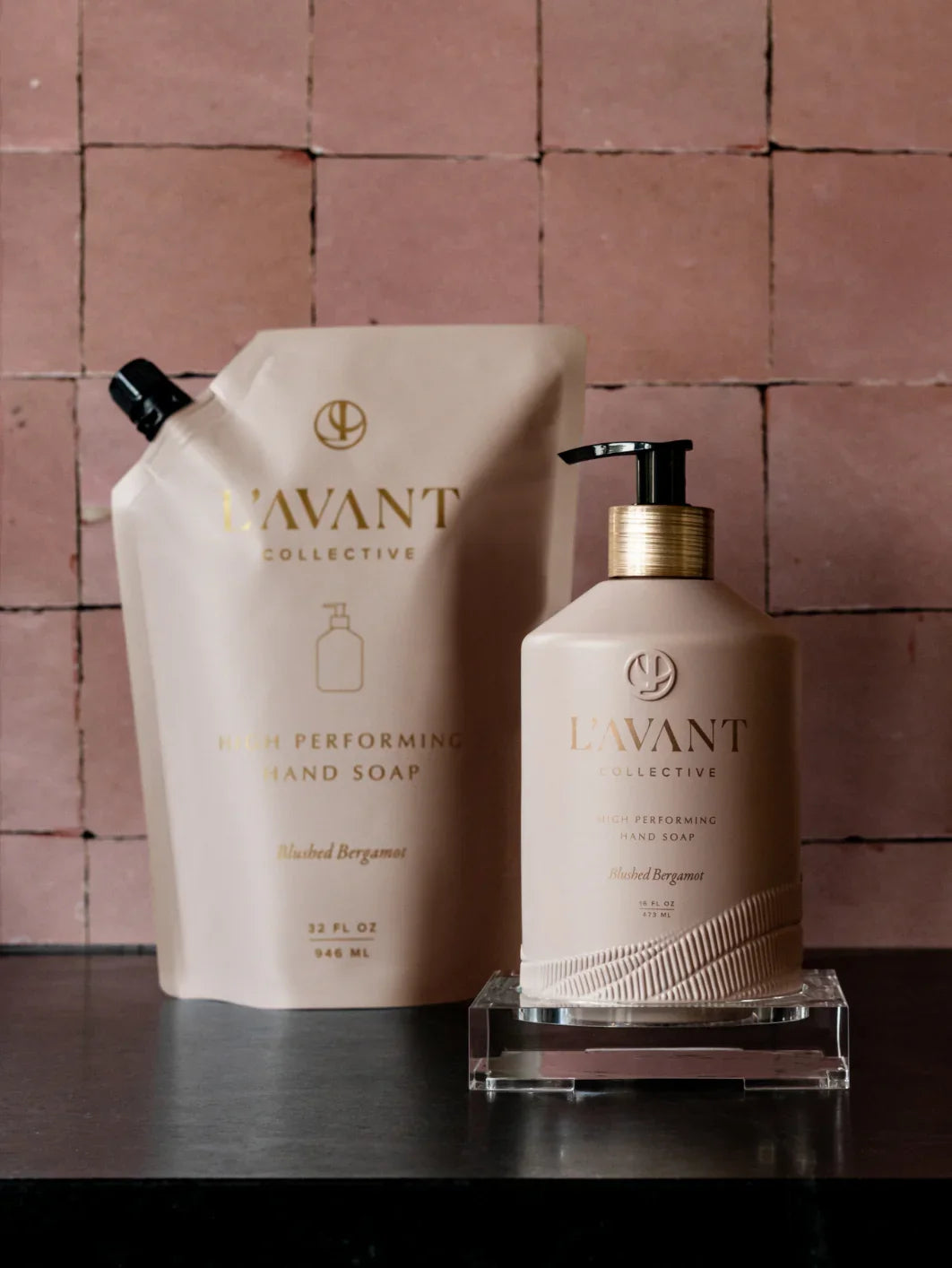 L'AVANT Collective High Performing Hand Soap bottles on black surface with pink tile background, Come see us at Awaken, Franklin, Tennessee