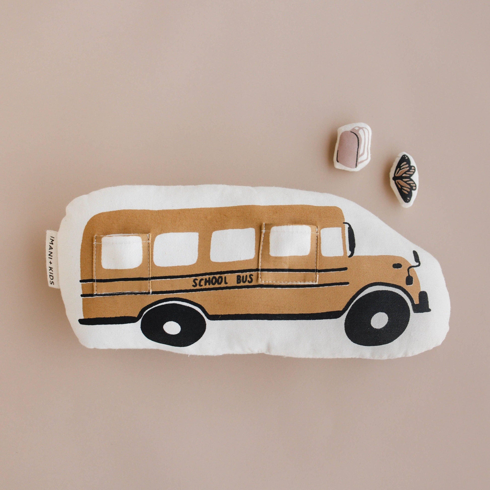 Plush school bus toy with backpack and butterfly patches on pale background, Come see us at Awaken, Franklin, Tennessee.
