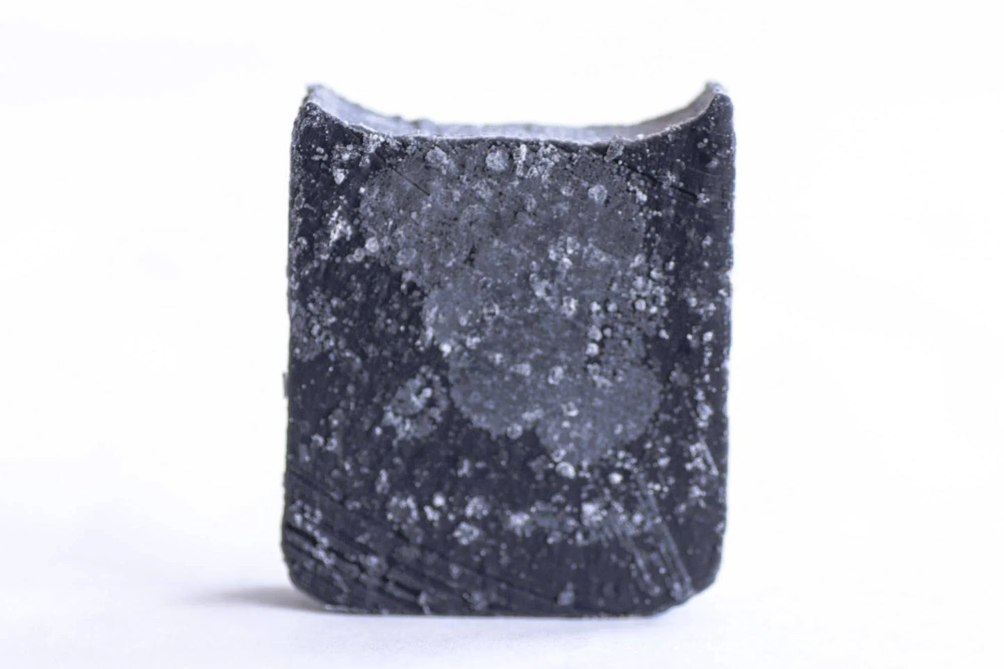 Black salt crystal cube with white mineral deposits on white background. Come see us at Awaken, Franklin, Tennessee