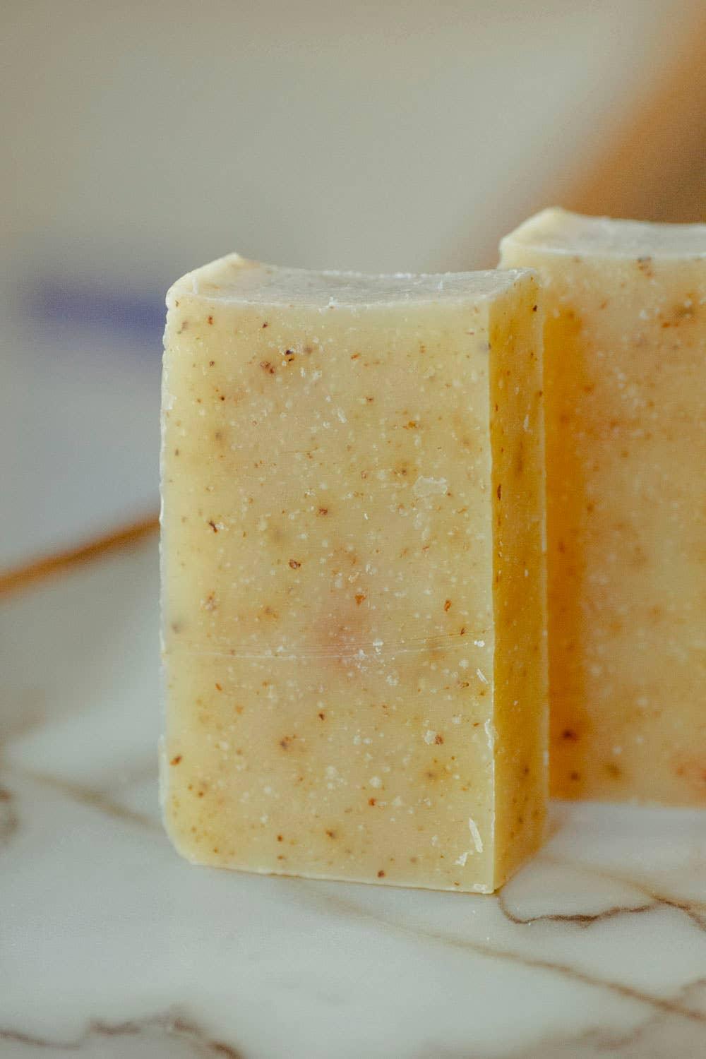 Close-up of natural exfoliating soap bar with speckles on marble surface. Come see us at Awaken, Franklin, Tennessee