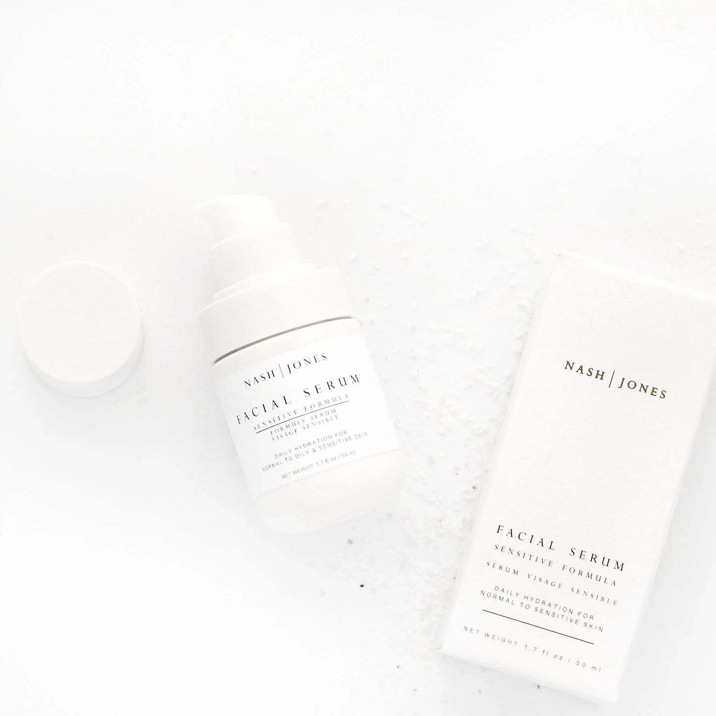 Nash Jones facial serum bottle and box on white surface with salt crystals, skincare product. Come see us at Awaken, Franklin, Tennessee